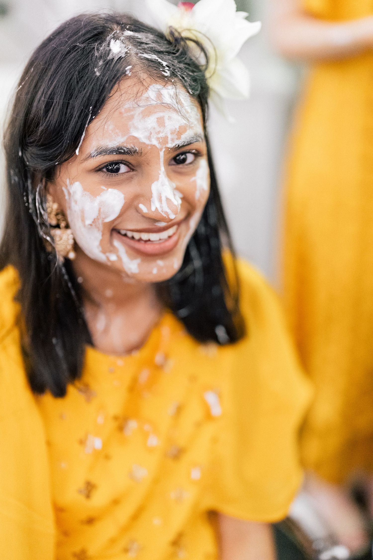 Person in yellow attire with white face paint smiling during a celebration.