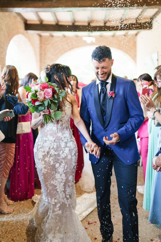 Wedding party celebrates with confetti and laughter in rustic venue.