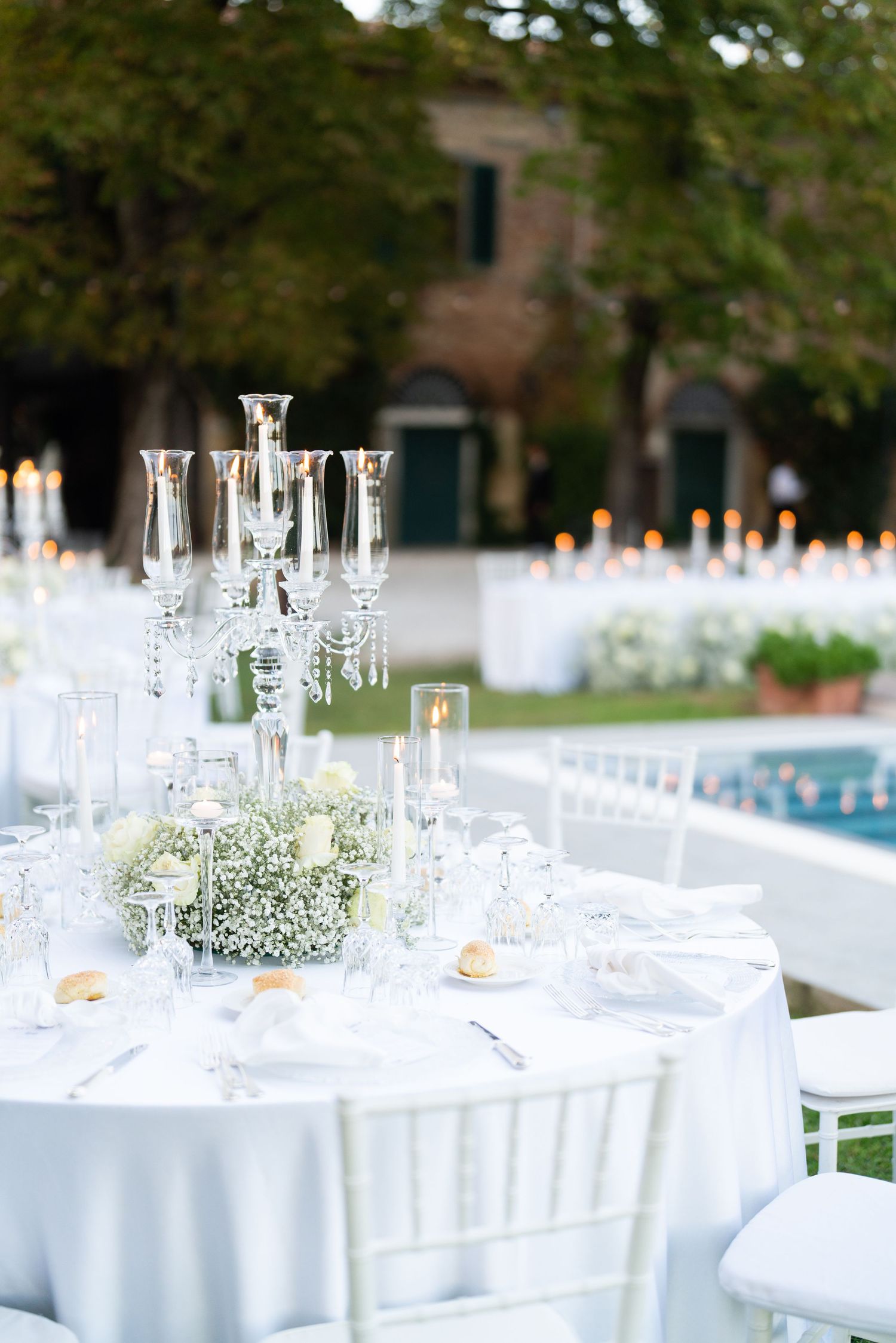 Elegant wedding reception tables with white linens, crystal glasses, and delicate baby's breath centerpieces.