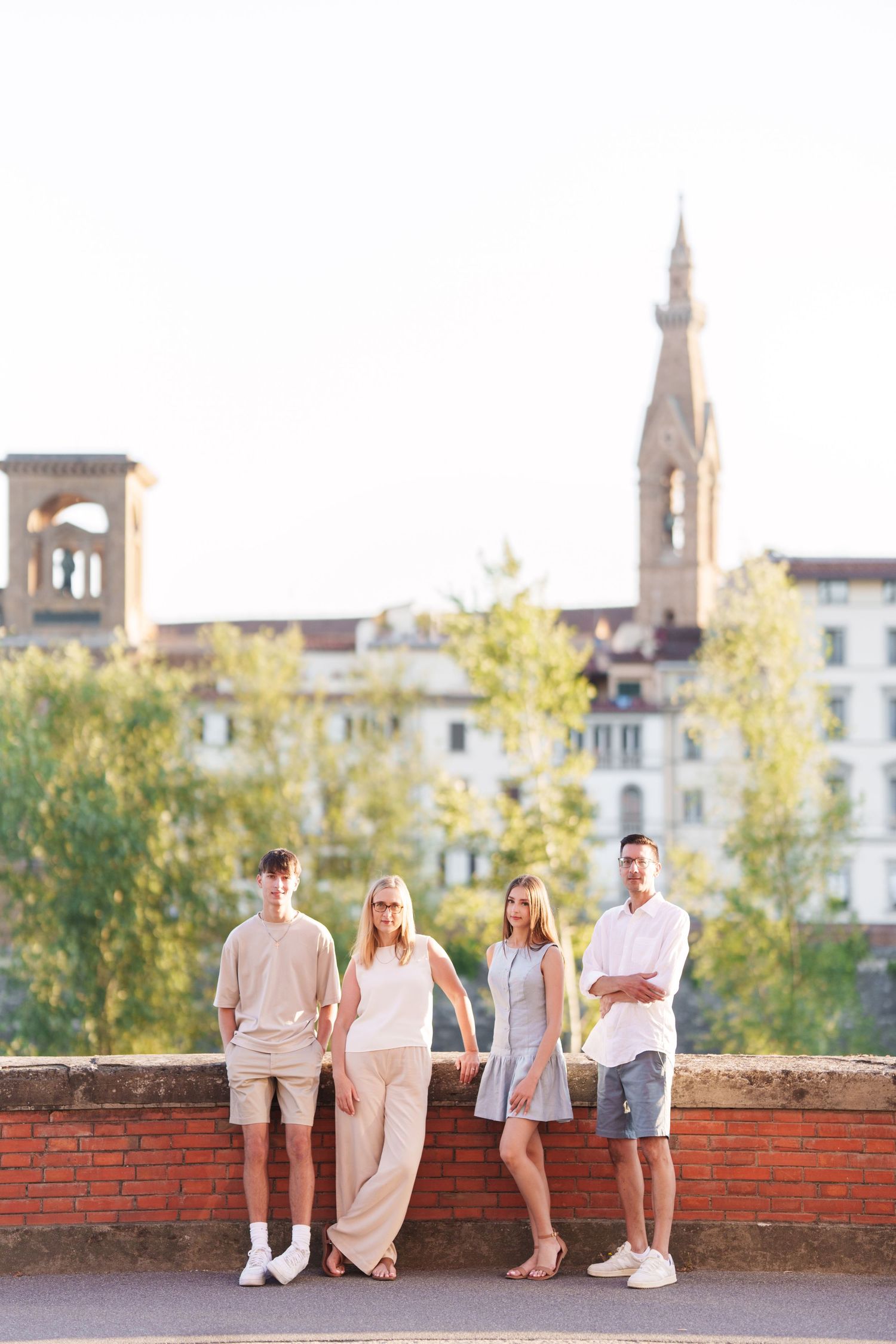 photographer Florence Group standing together on a brick wall with historic Italian architecture and church spire visible in background.
