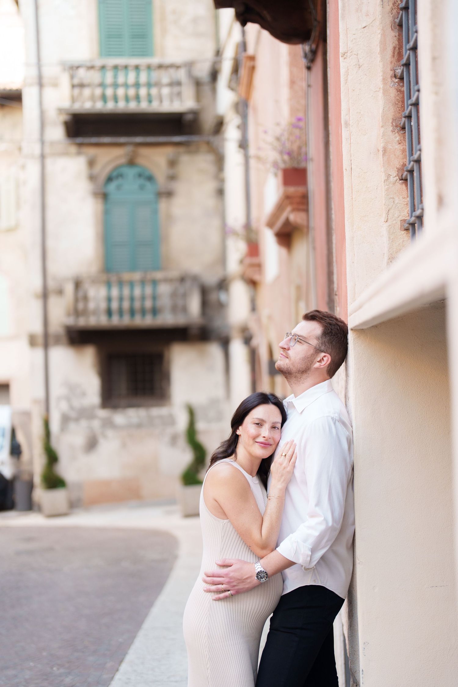 A romantic couple shares tender moments in a series of photos against an old European building facade.