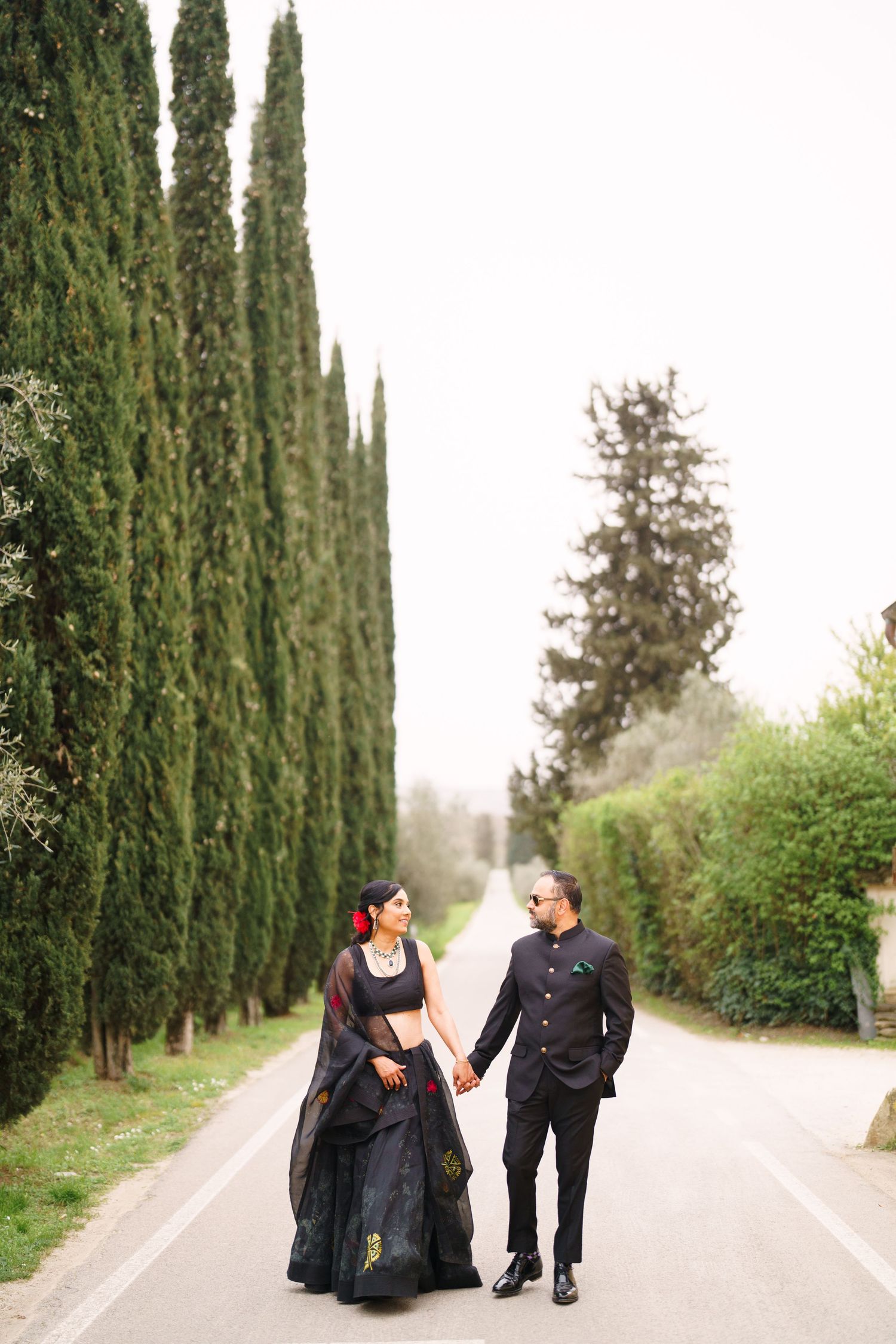 A couple shares a romantic moment along a cypress tree-lined road in the countryside.