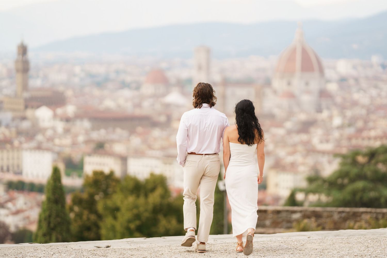 Couple enjoying a romantic view of Florence, Italy with the iconic Duomo cathedral dome visible in the distance.