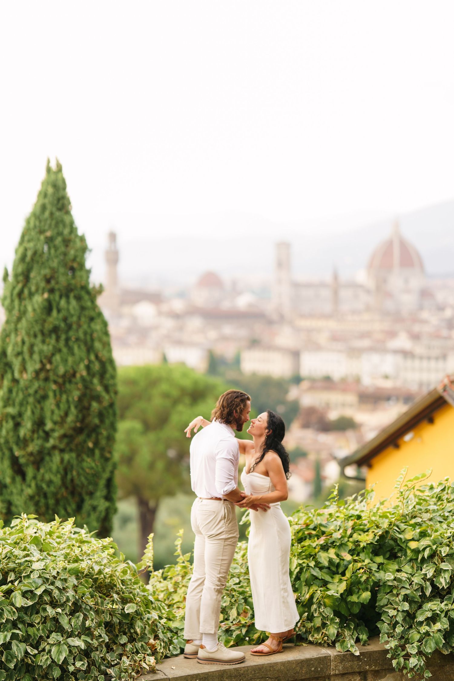 A couple shares a romantic moment overlooking the historic skyline of Florence, Italy from Piazzale Michelangelo.