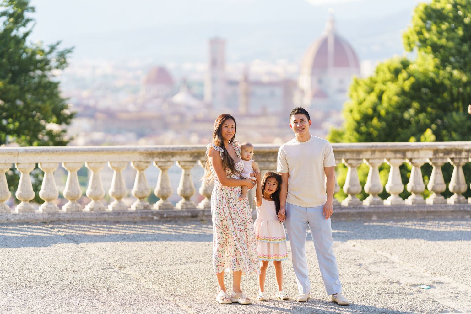 Family of four posing at Piazzale Michelangelo with Florence skyline and Duomo cathedral in background.