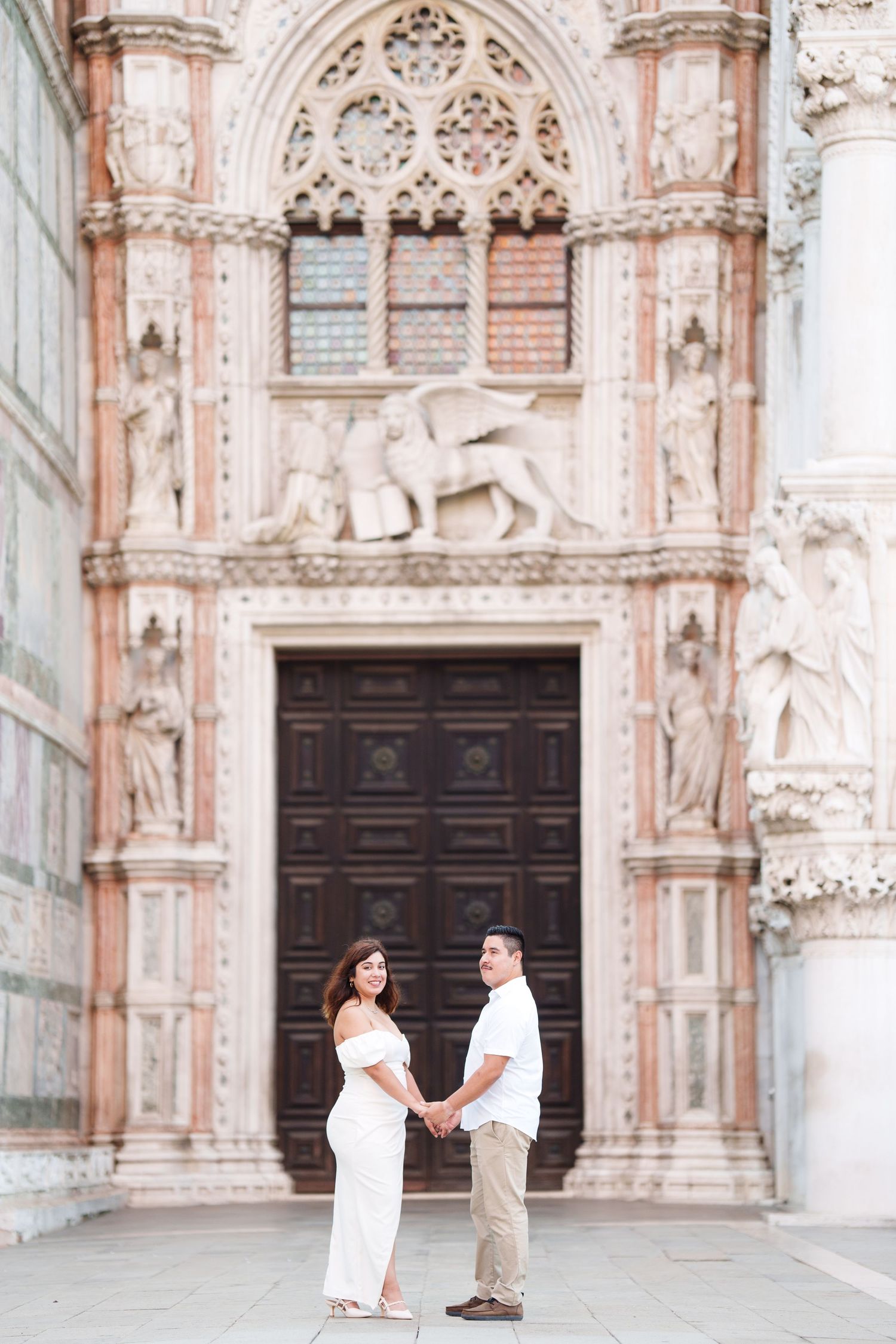 A romantic proposal moment captured in front of an ornate Gothic cathedral with intricate stone carvings and arched doorways.