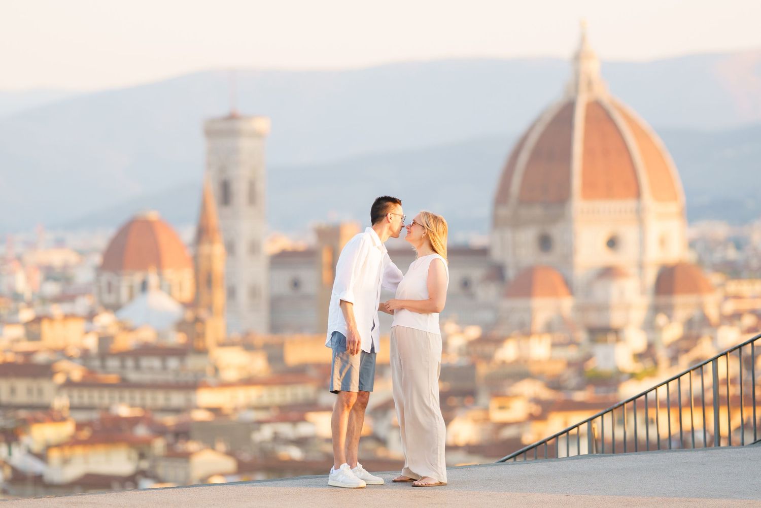 A couple shares a romantic moment overlooking Florence, Italy with the iconic Duomo cathedral dome in the background.  photographer Florence