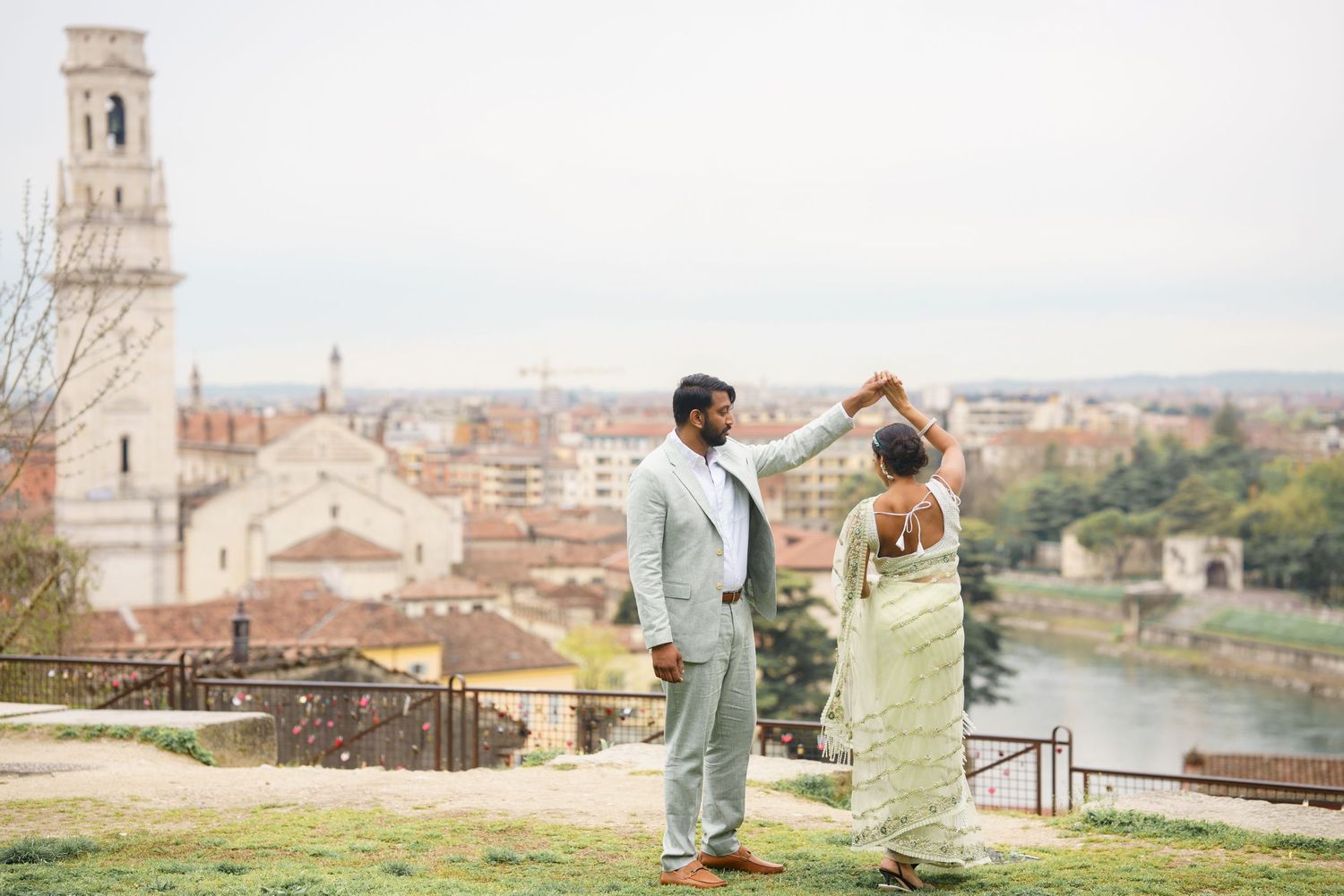 A couple poses together in Florence, Italy with the historic cityscape and Arno River visible in the background.