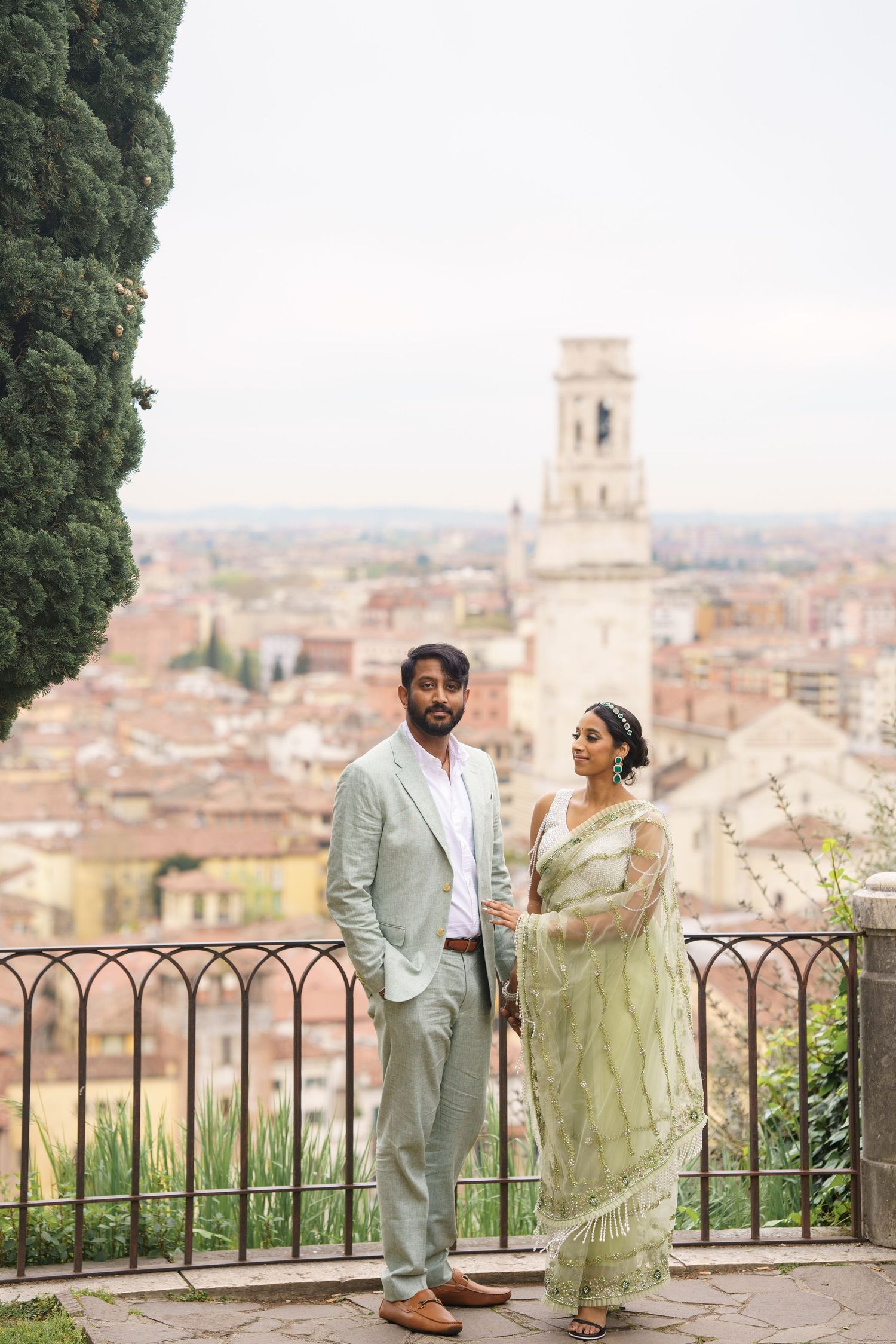 A couple enjoying a scenic overlook of a historic Italian cityscape with terracotta roofs and church towers in the background.