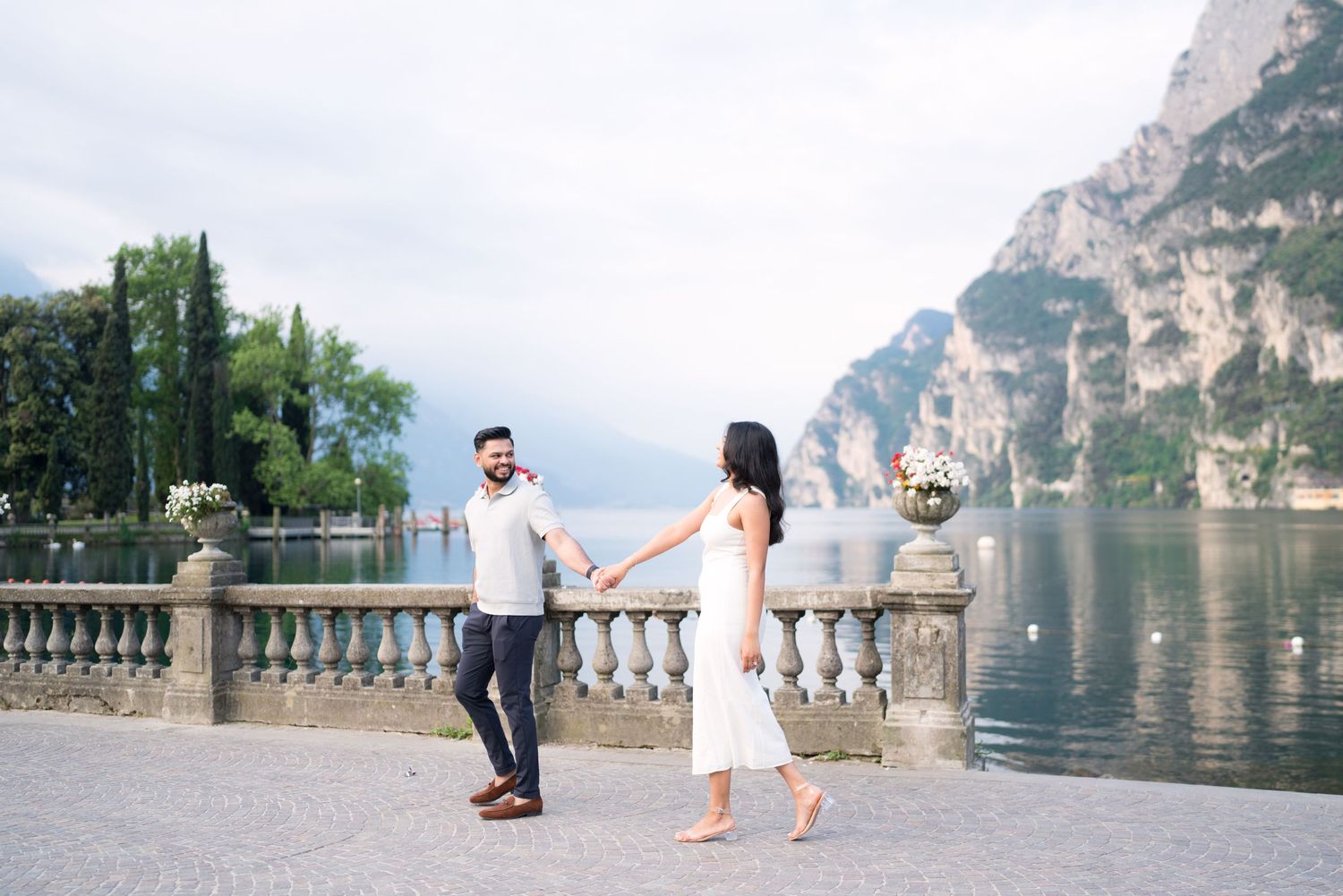 Romantic couple shares special moments at Lake Garda in Italy with stunning mountain views and lakeside scenery.
