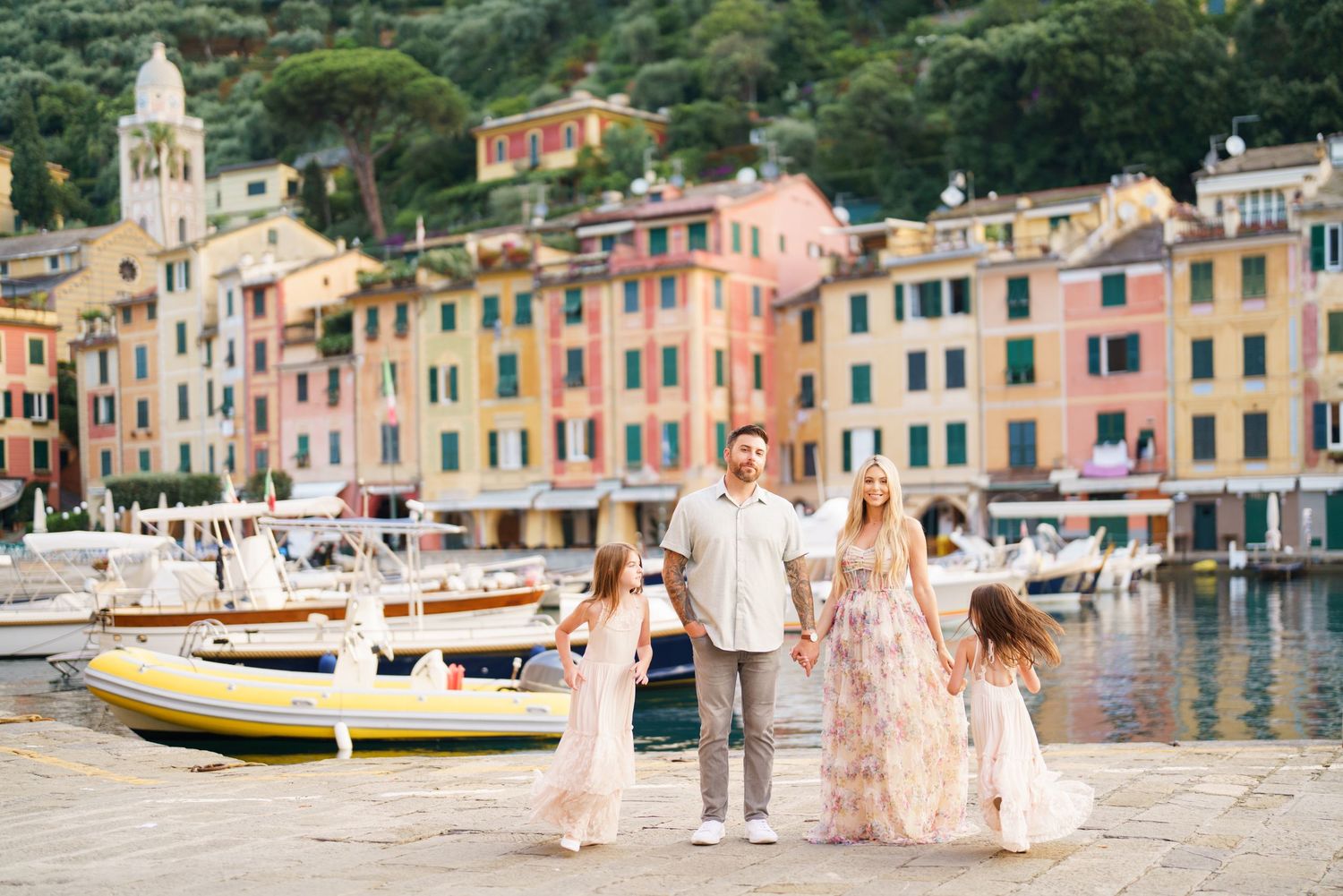 Colorful historic buildings line the waterfront of Portofino, Italy with boats docked in the harbor on a sunny day.