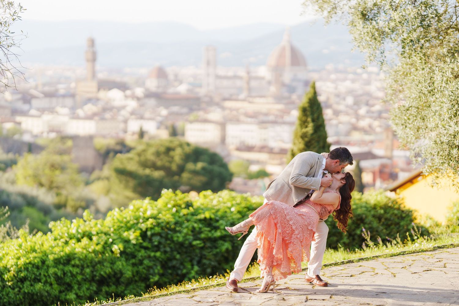 A romantic couple shares a tender moment overlooking the scenic cityscape of Florence, Italy with the Duomo visible below.
