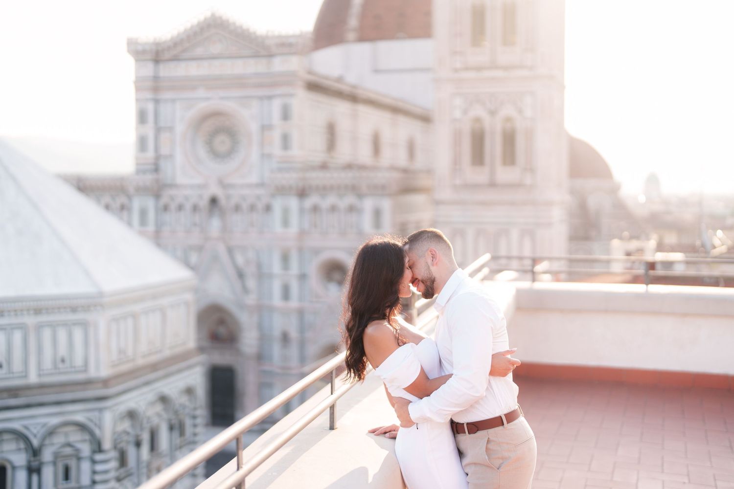A couple shares a romantic moment on a rooftop overlooking Florence Cathedral during golden hour.