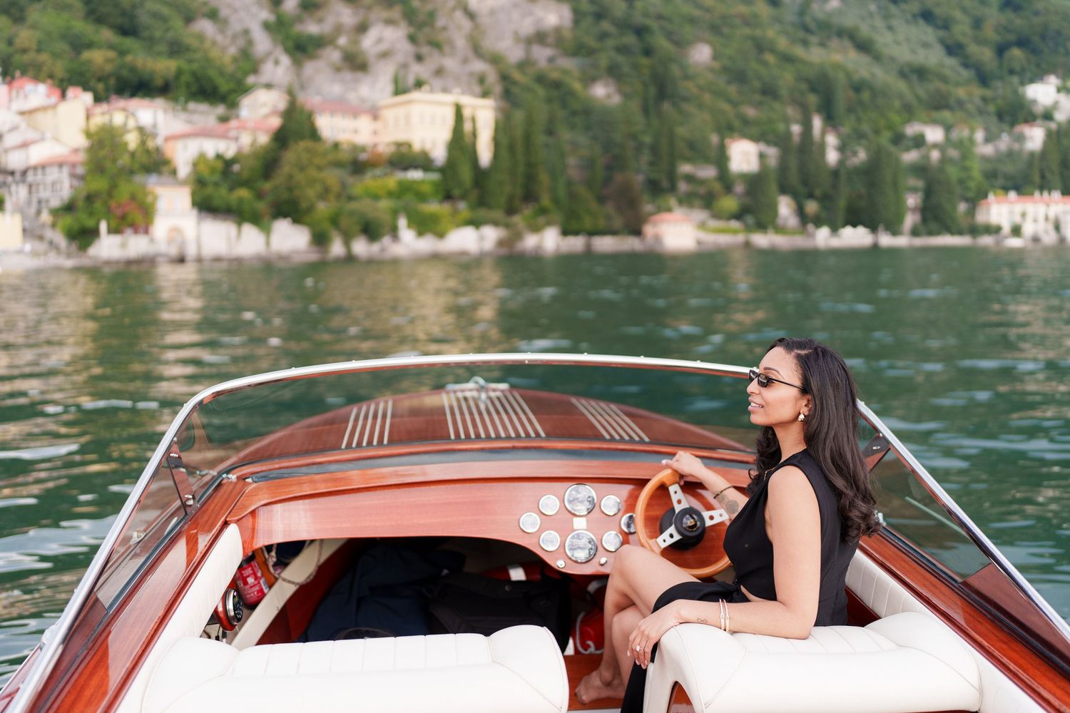Wooden boat cruising across Lake Como in Italy with scenic mountain views and coastal villas in the background.