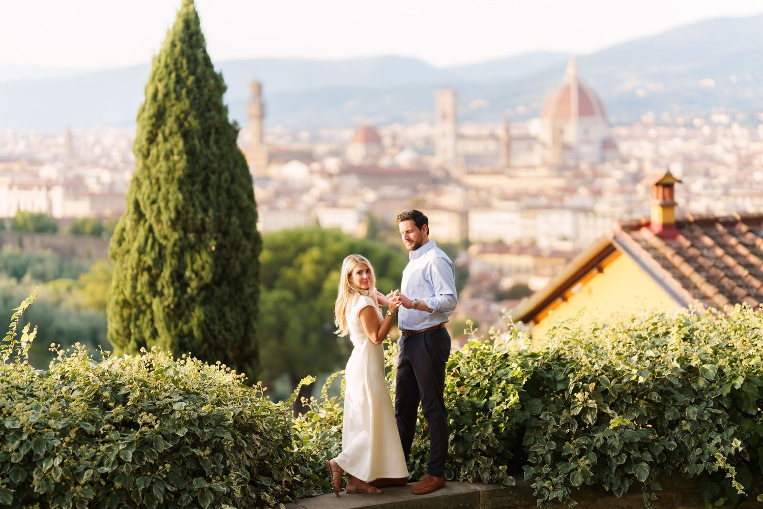A romantic couple enjoys a scenic view of Florence, Italy with the iconic Duomo cathedral visible in the distance.