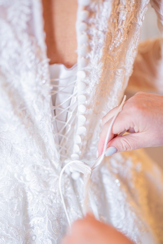 Close-up details of intricate white lace wedding dress fabric.