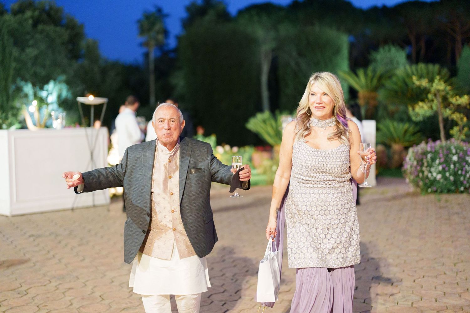 Guests enjoying an outdoor evening garden party with string lights and decorative elements.
