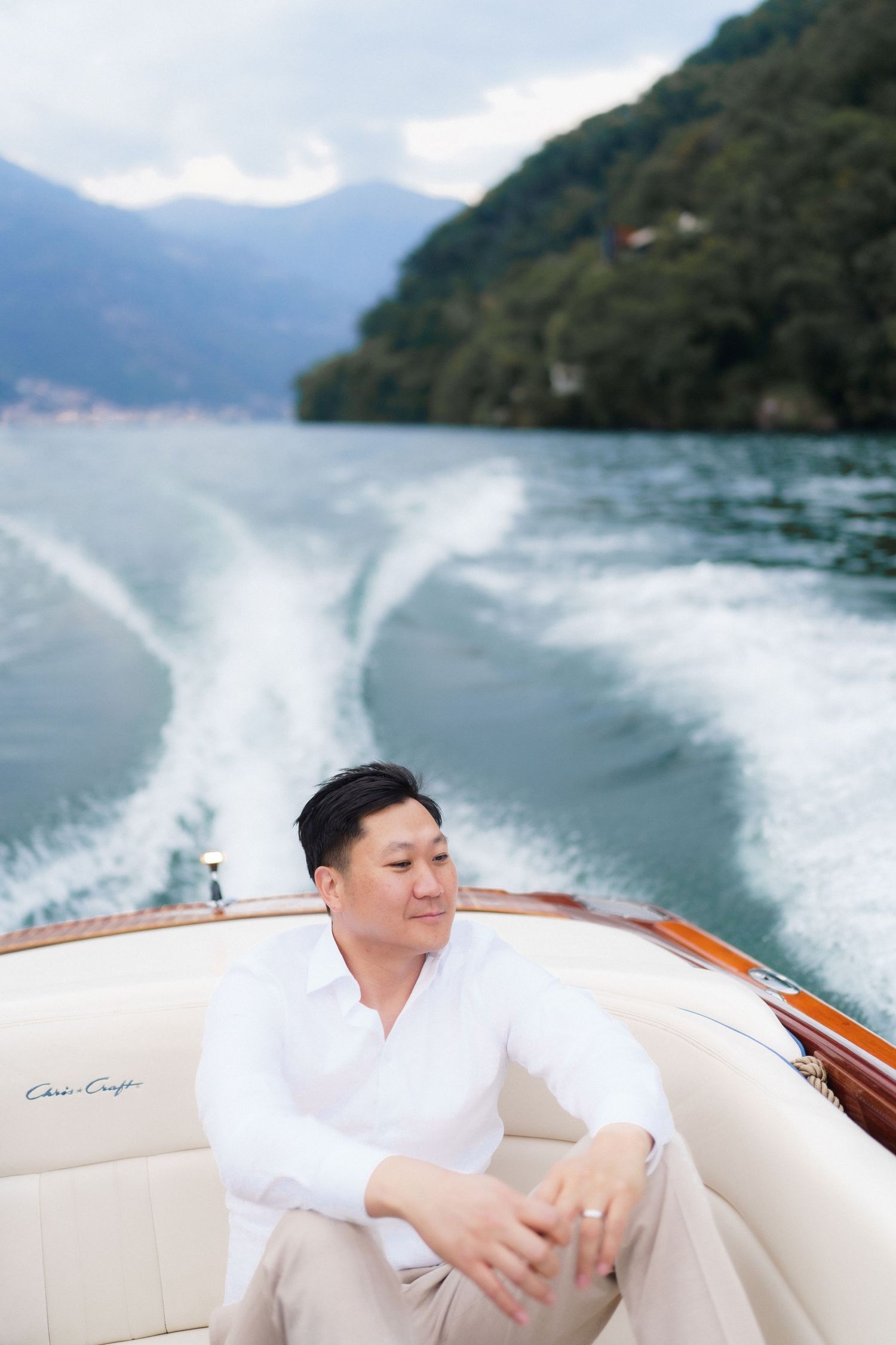 A person relaxes on a luxury boat while cruising through scenic mountain waters on a bright day.