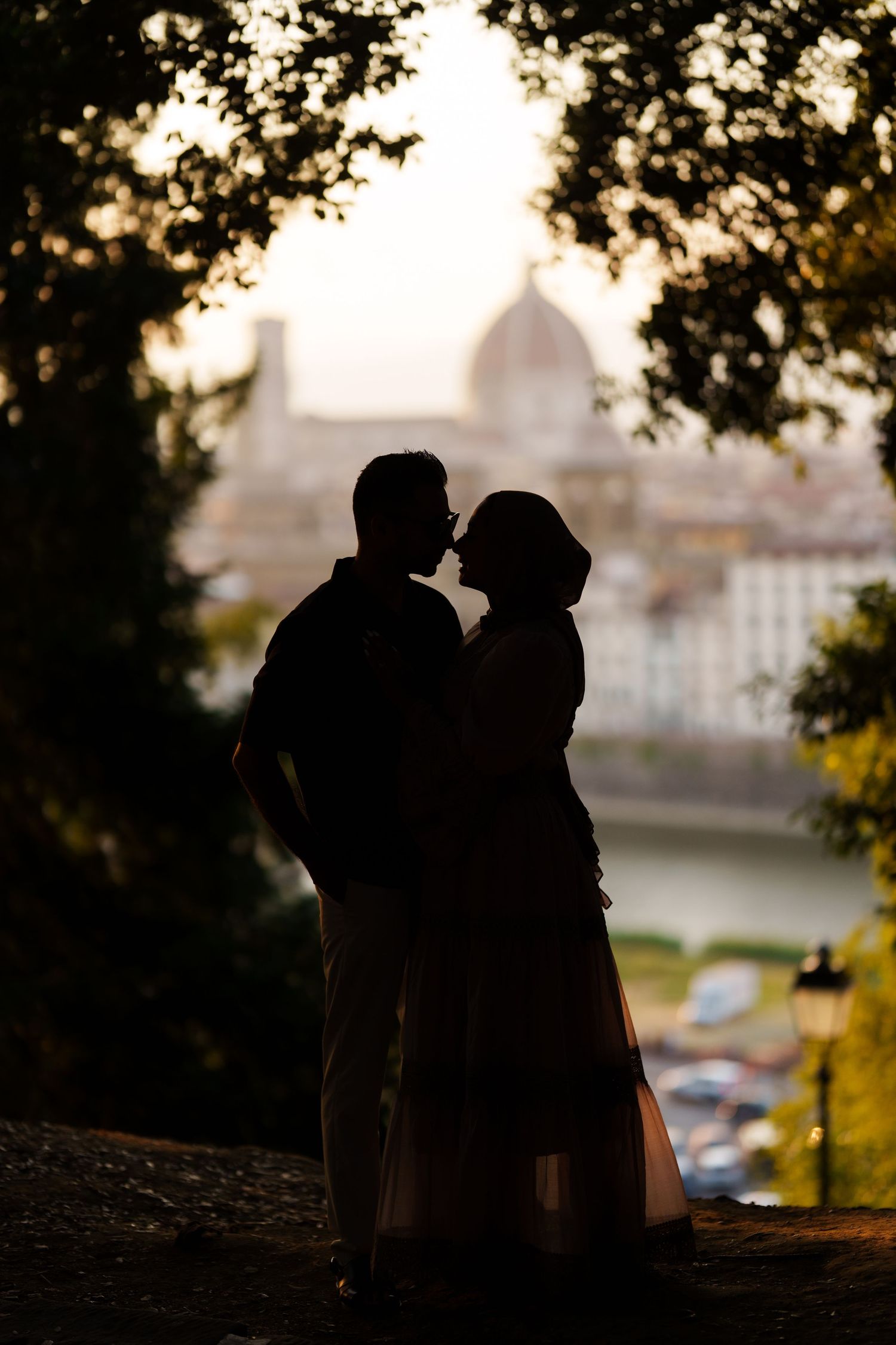 Romantic silhouette of a couple about to kiss with Florence cathedral dome and Arno River at sunset.
