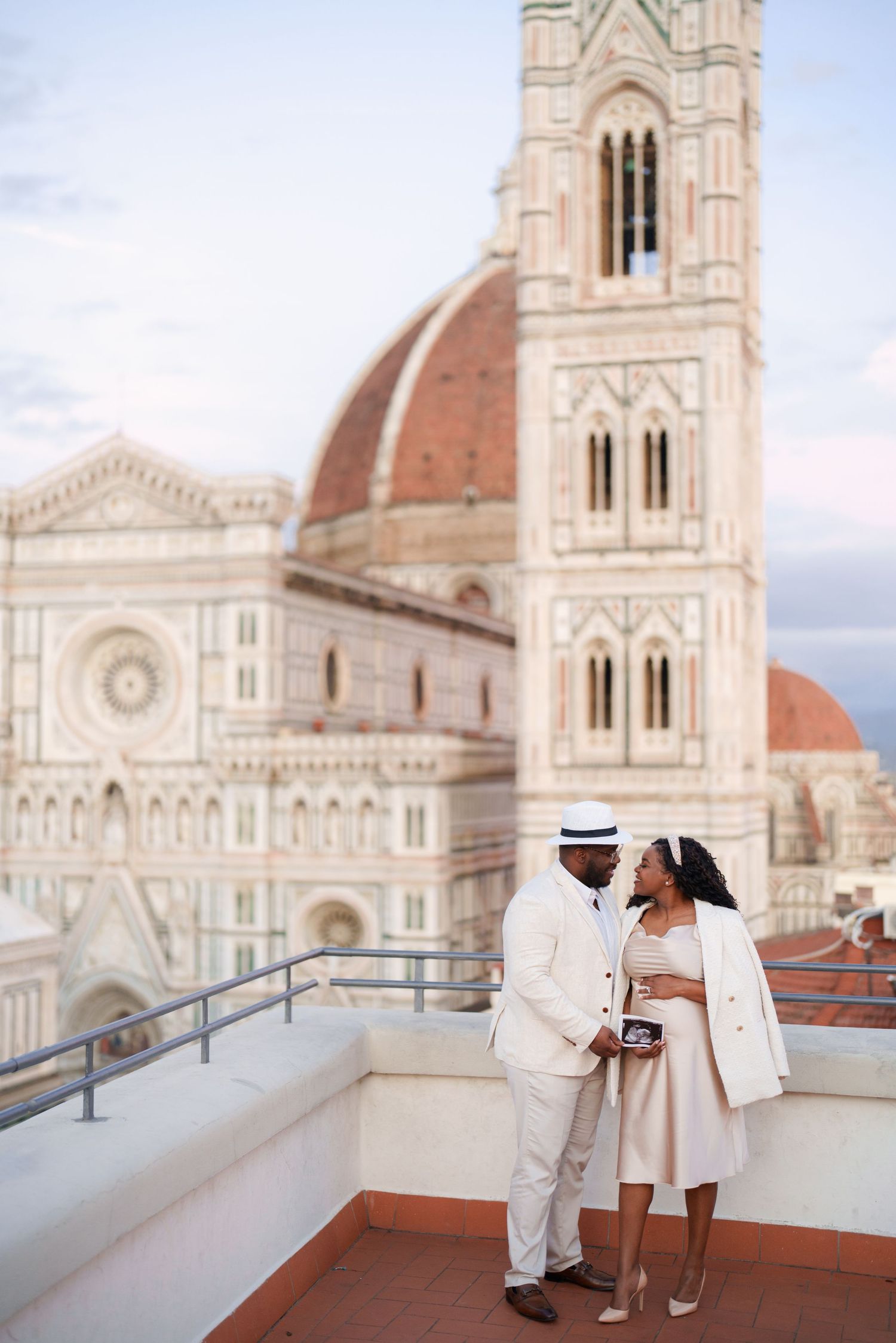 Elegant couple posing on a rooftop terrace with Florence Cathedral and Giotto's Campanile backdrop.