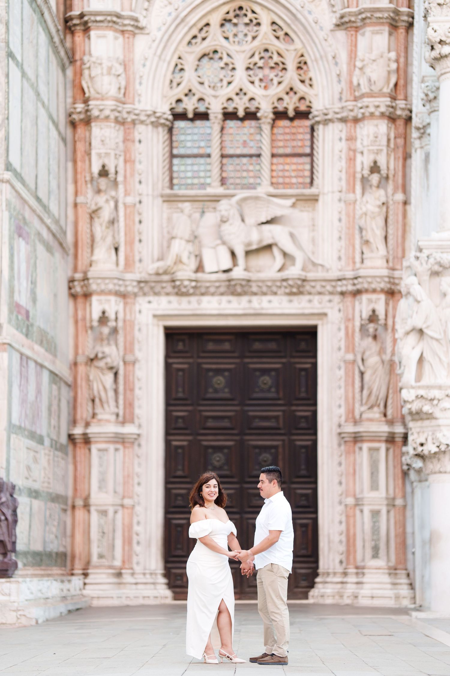 Elegant architectural entrance of an Italian cathedral with ornate stone carvings and a dark wooden door.