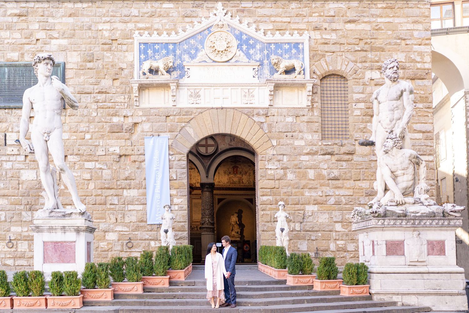 Elegant entrance to Palazzo Vecchio in Florence with classical statues and ornate archway framed by decorative details.