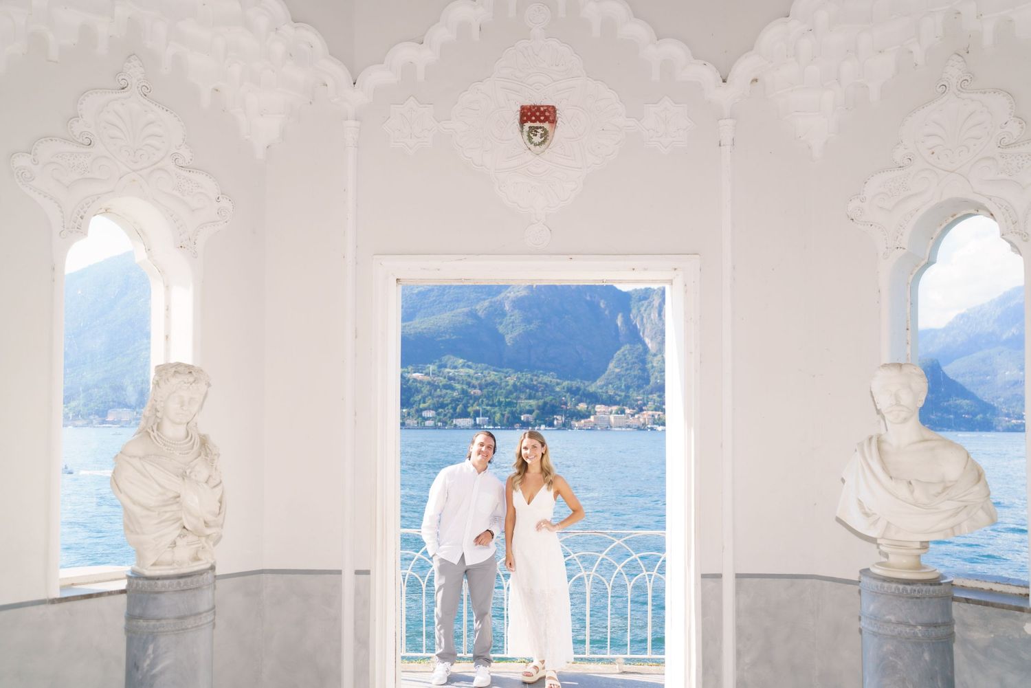 A scenic wedding venue with white columns overlooking a coastal mountain landscape and blue waters.