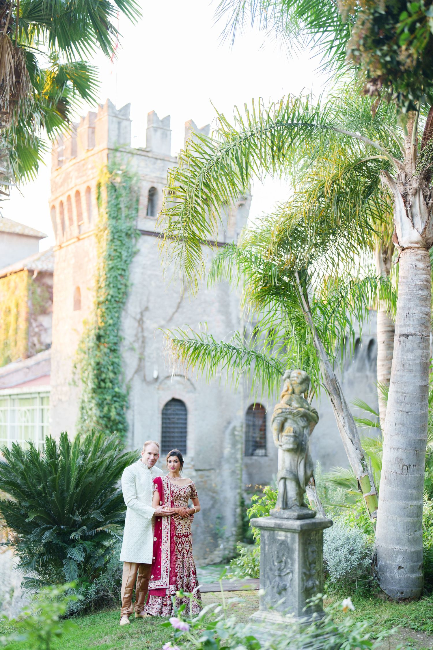 A romantic portrait session in front of a historic building with tropical landscaping and stone sculptures.