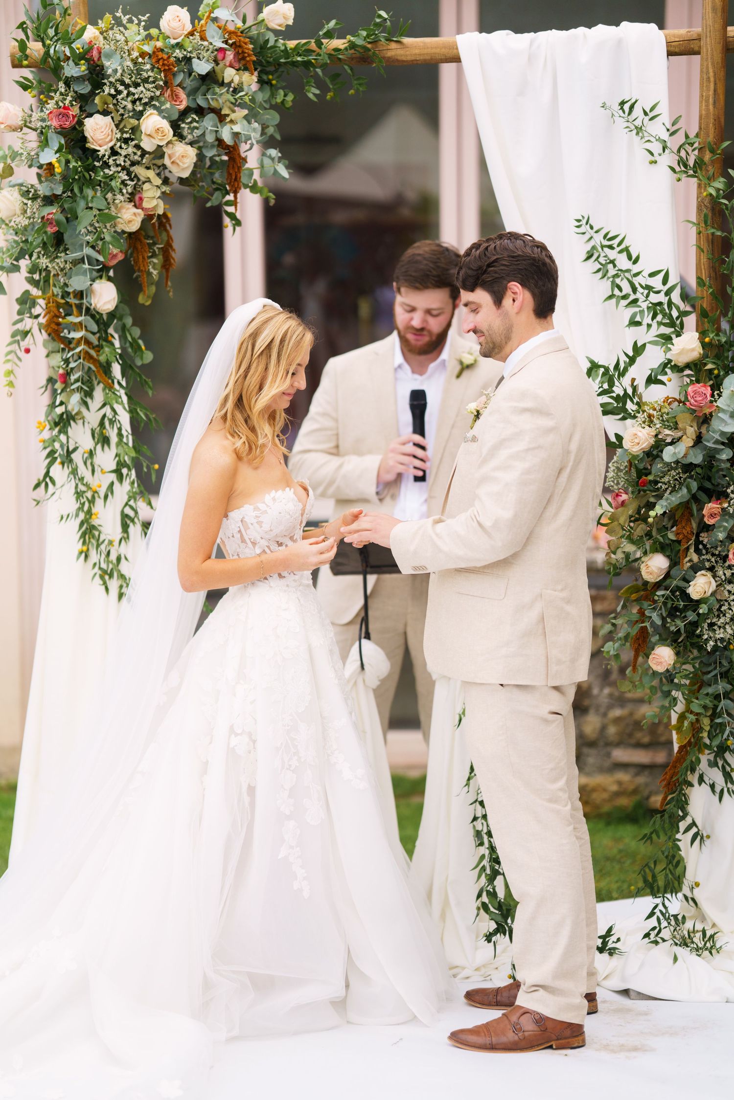 Wedding ceremony moment captured under an elegant floral arch with pink and white blooms.