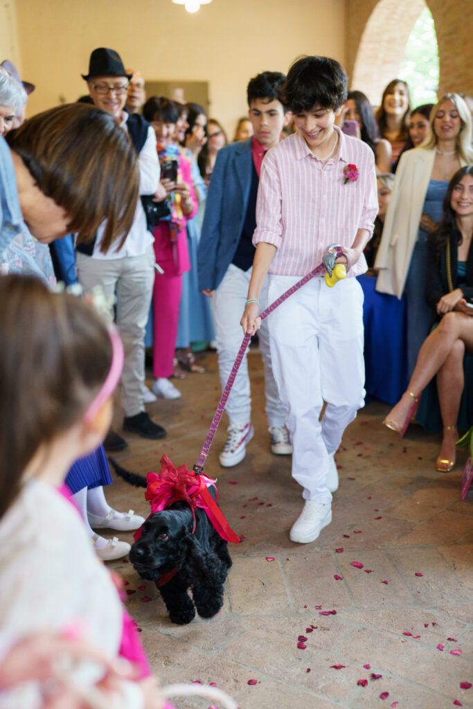 Wedding guests mingle on a stone floor with scattered rose petals during the celebration.