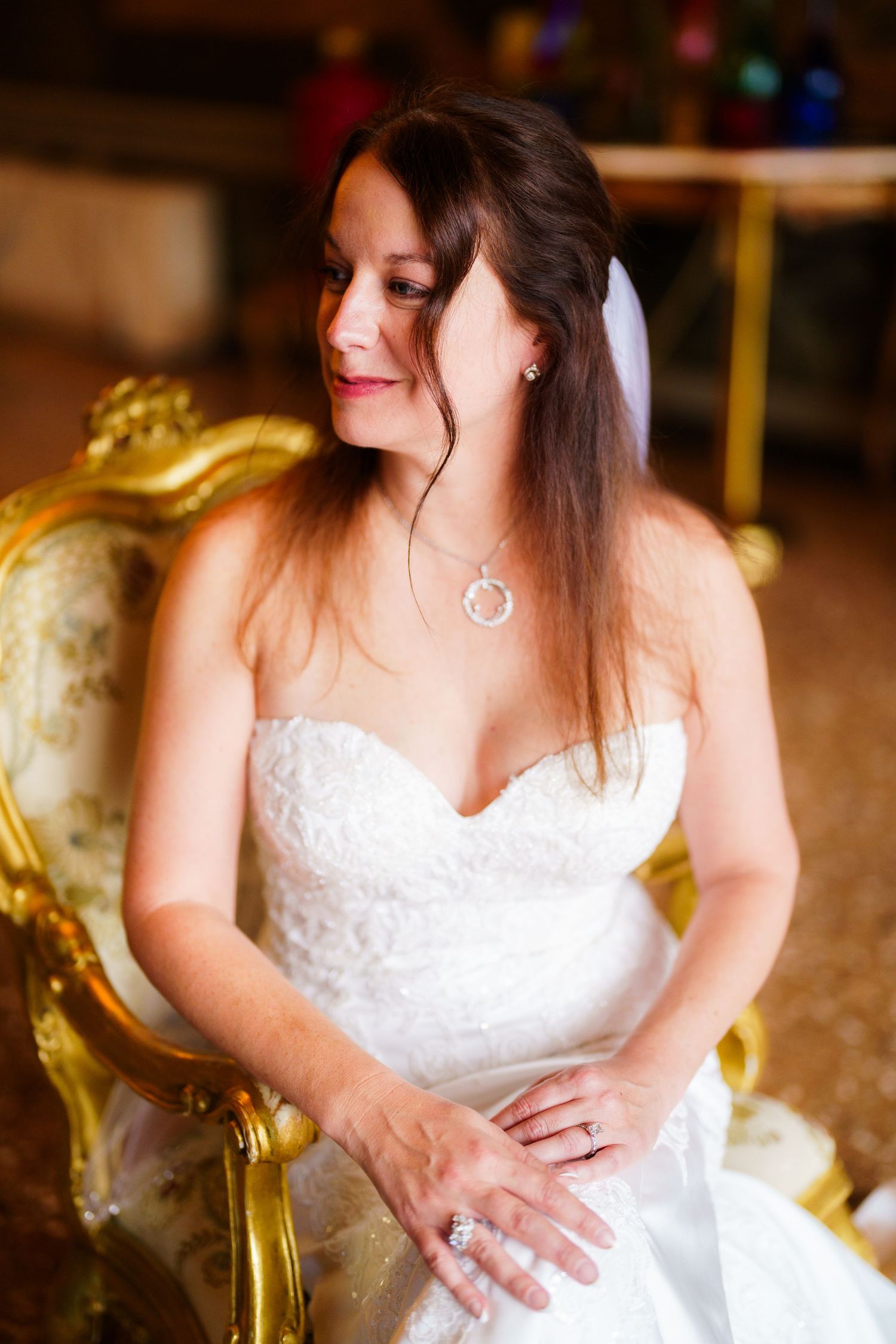 A wedding dress detail shot shows delicate white lace and elegant fabric in warm indoor lighting.