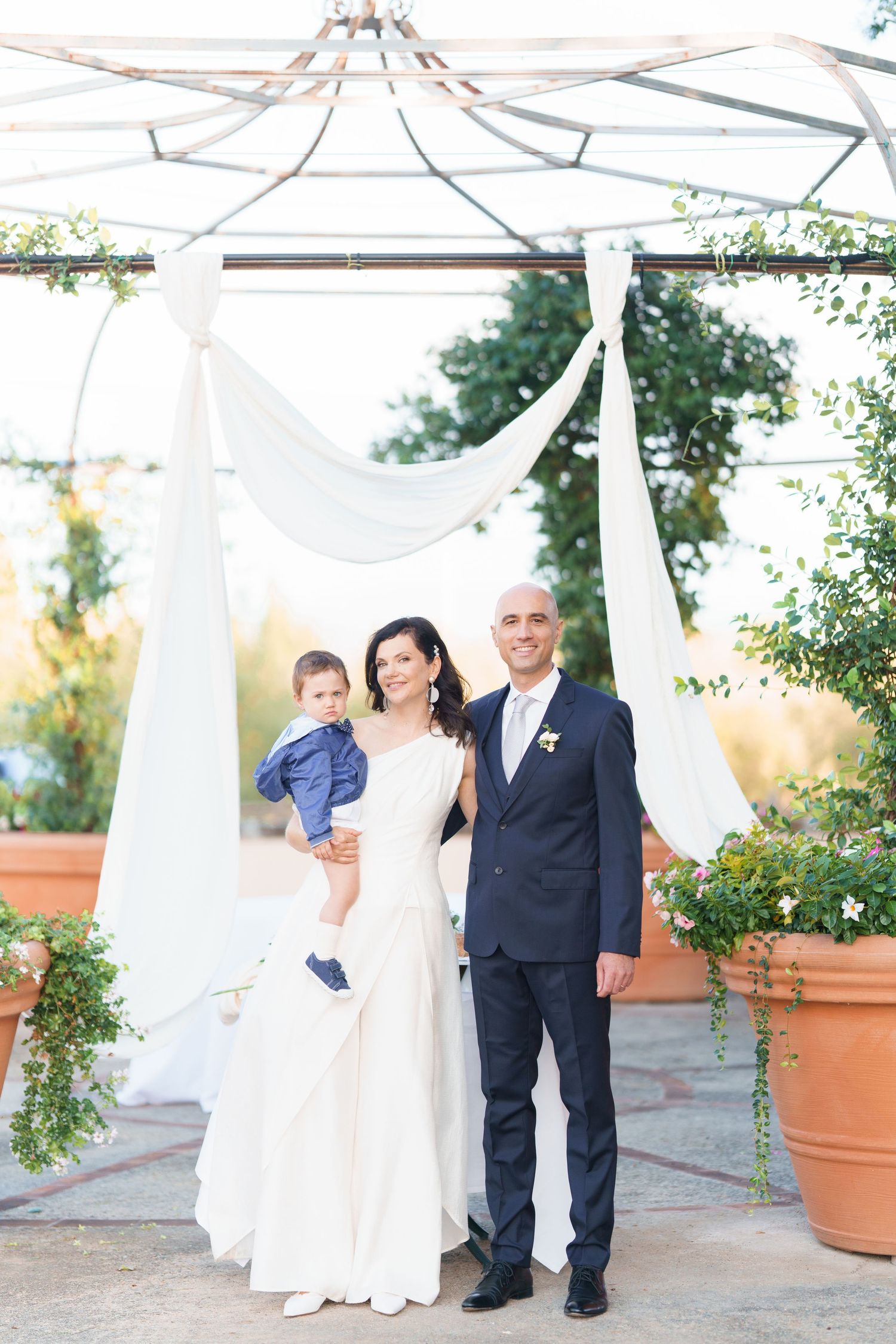 Outdoor wedding photos with white draped canopy and terra cotta planters in garden setting.
