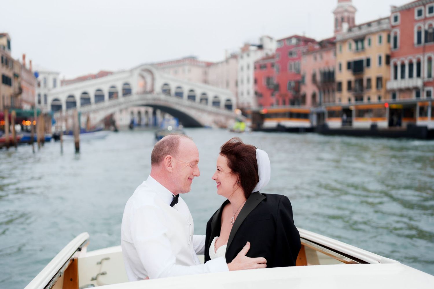 Romantic couple shares tender moments while riding in a gondola through Venice's scenic canals and waterways.