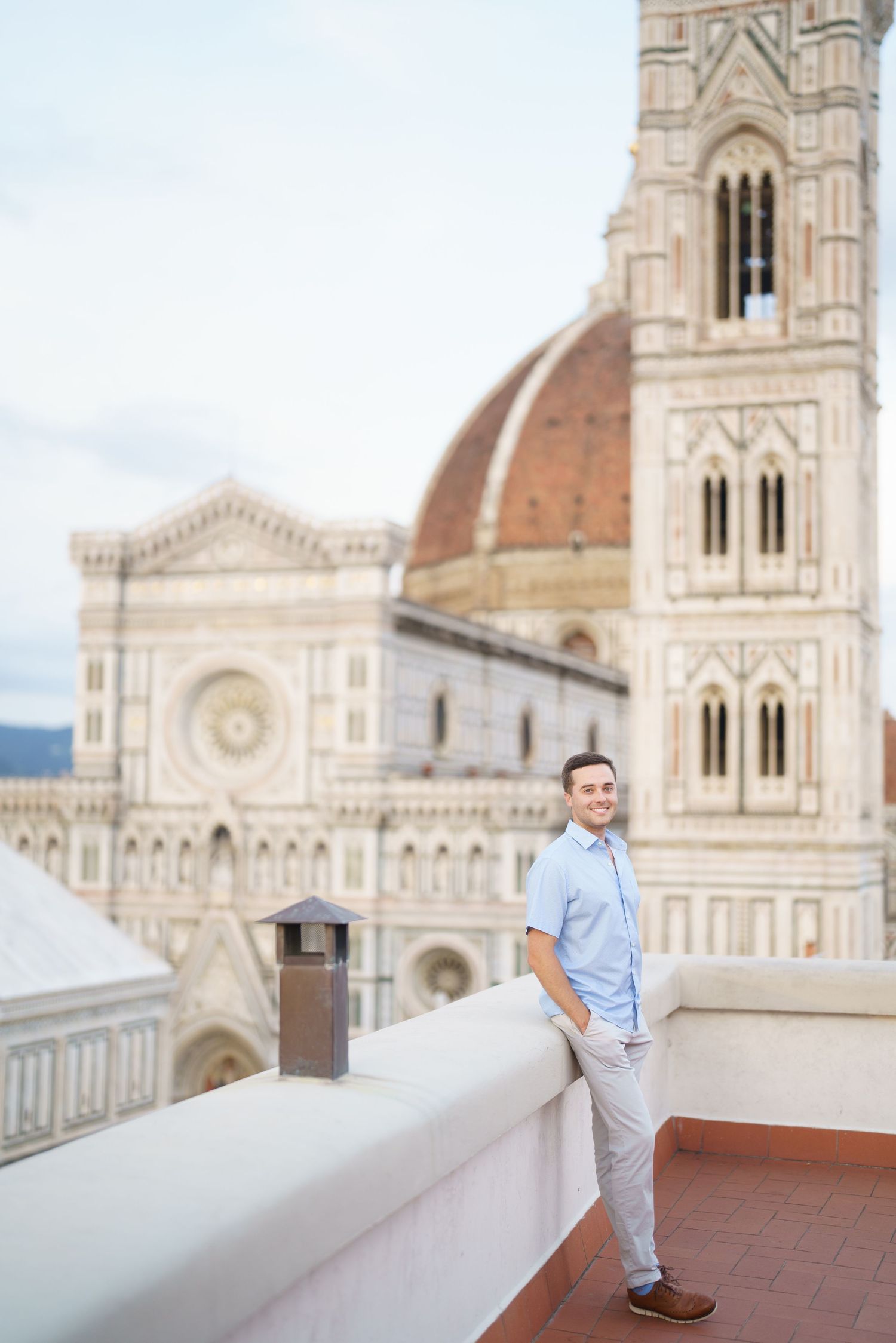 Tourist enjoying panoramic views from rooftop terrace overlooking Florence Cathedral and historic city architecture.