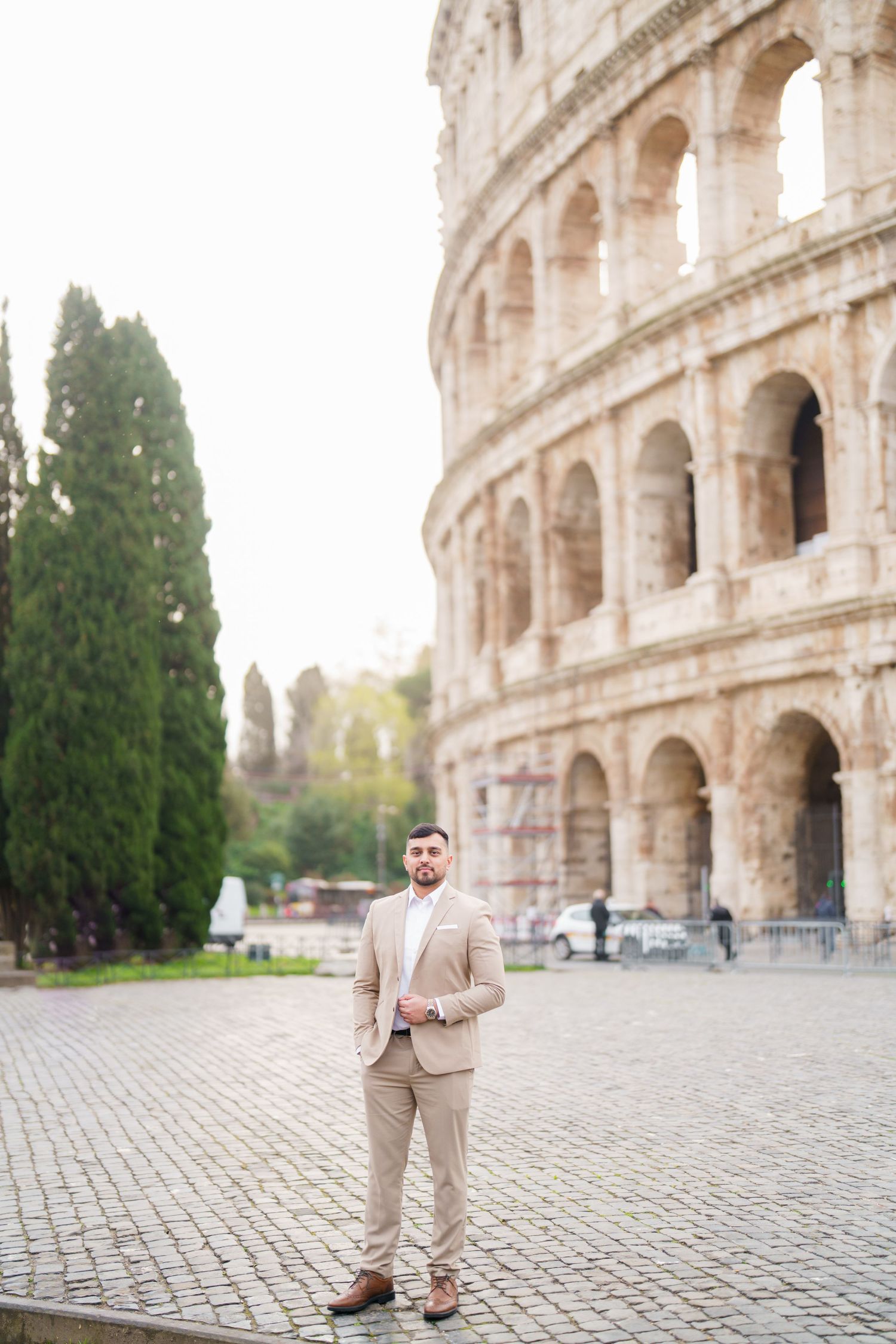 Elegant man in beige suit standing in front of the Colosseum in Rome, Italy.