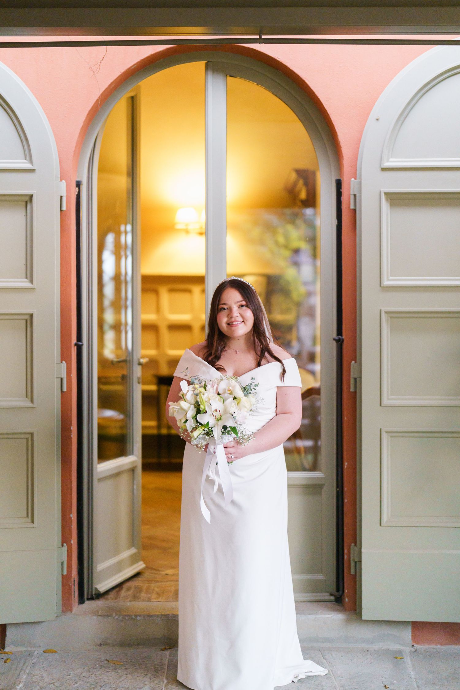 White-dressed figure posing in doorways along a warmly lit corridor with arched entryways.