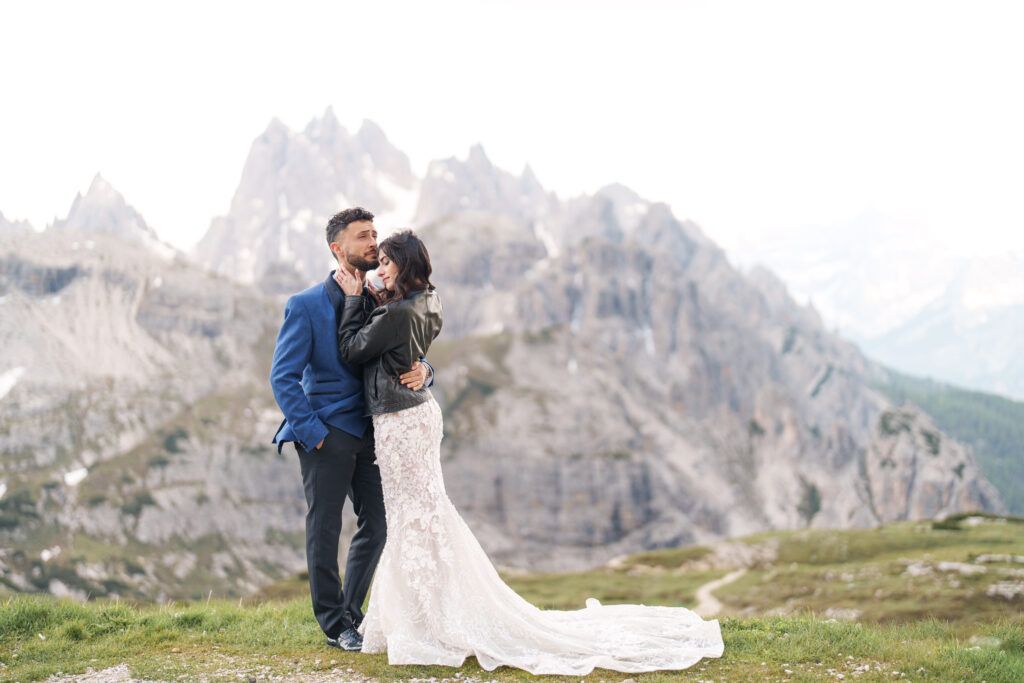 A romantic wedding portrait on a mountain ridge with sweeping views of jagged alpine peaks.