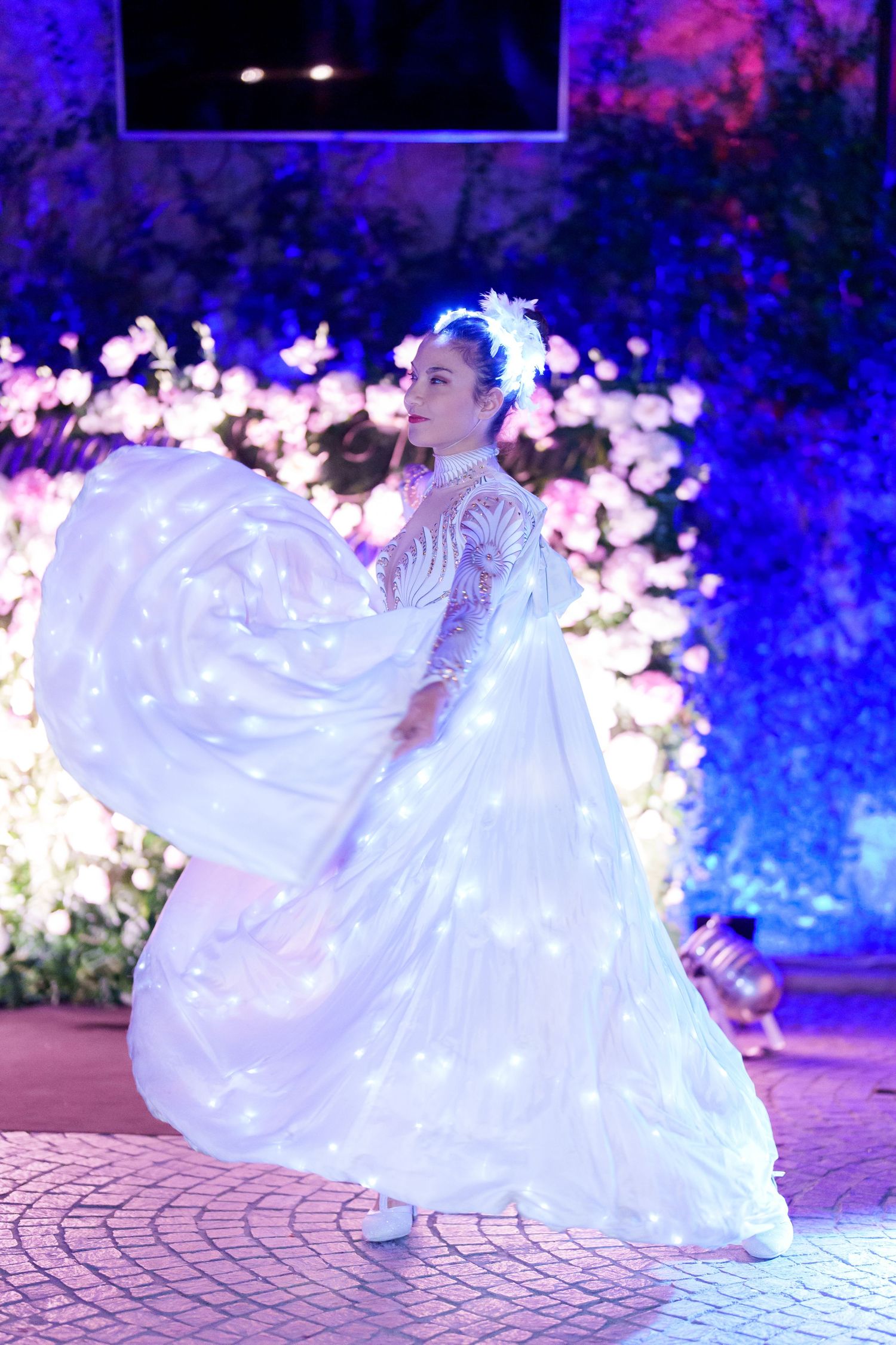 Flowing white dress twirling on illuminated dance floor with dramatic blue lighting effects.