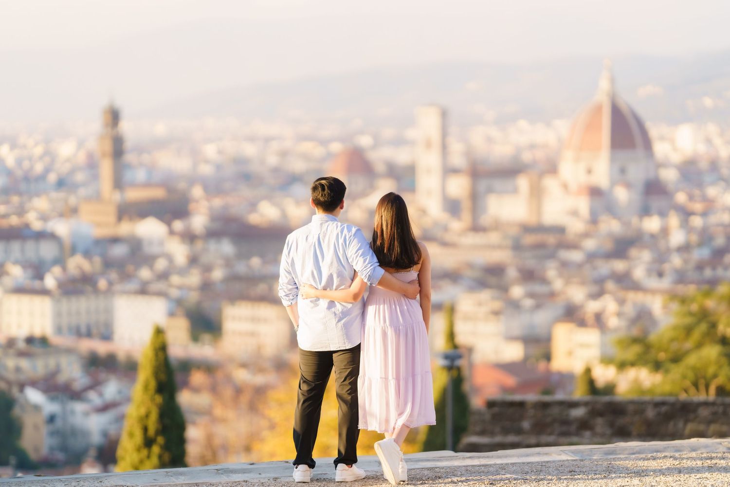 A couple admires the stunning cityscape of Florence, Italy with the iconic Duomo cathedral visible in the distance.