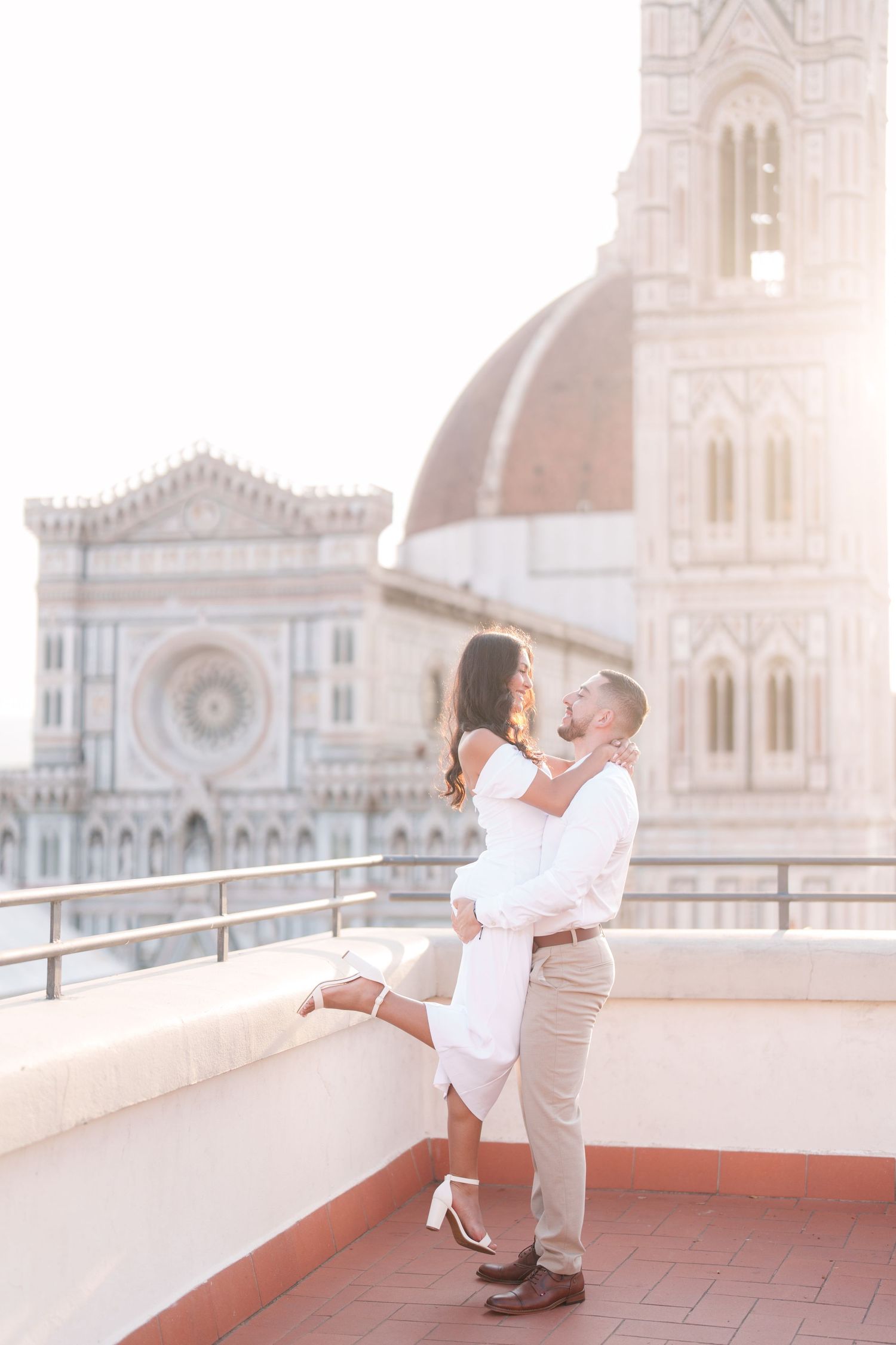 Romantic couple embracing on rooftop terrace overlooking Florence Cathedral and Duomo during sunset in Italy.