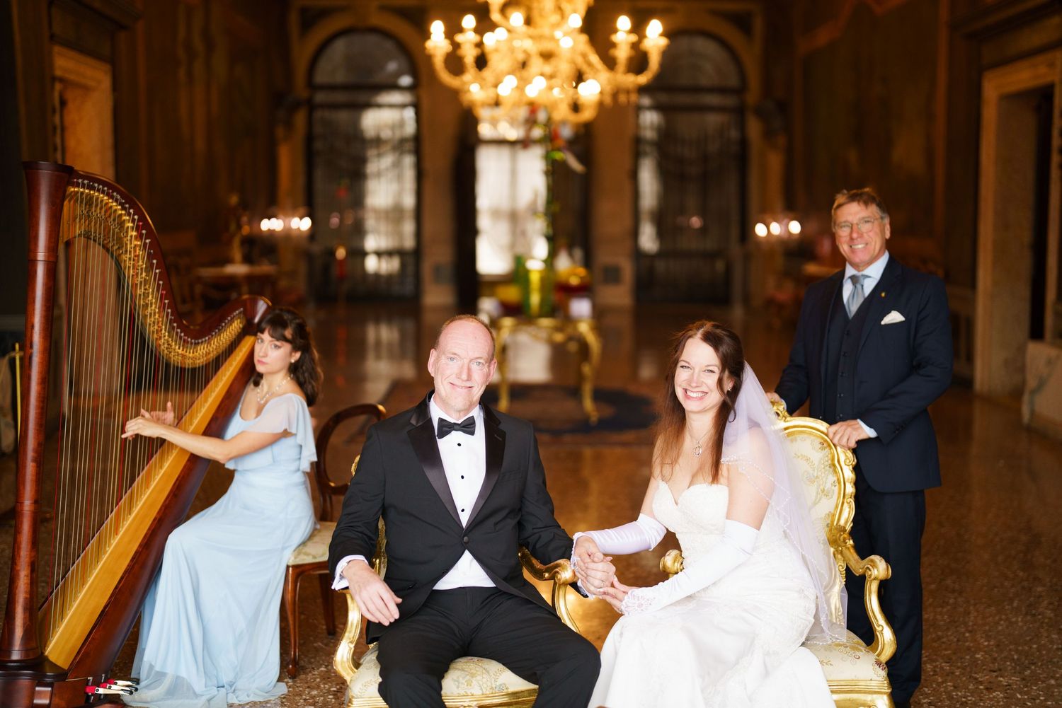 Elegant wedding reception in a grand ballroom with ornate chandeliers and couples dancing on the dance floor.