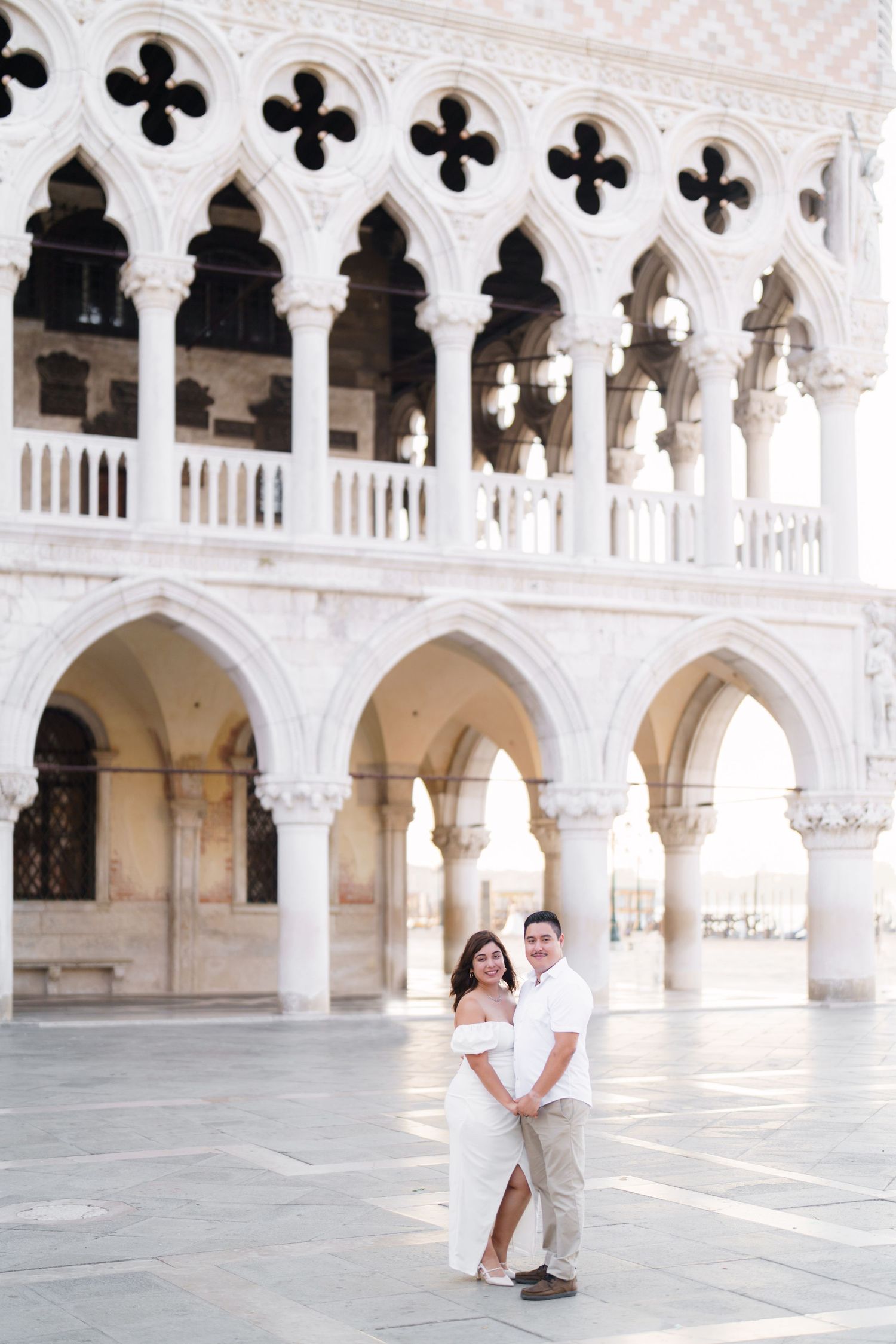 Couple poses together in romantic photoshoot at Doge's Palace courtyard in Venice with ornate Gothic architecture.