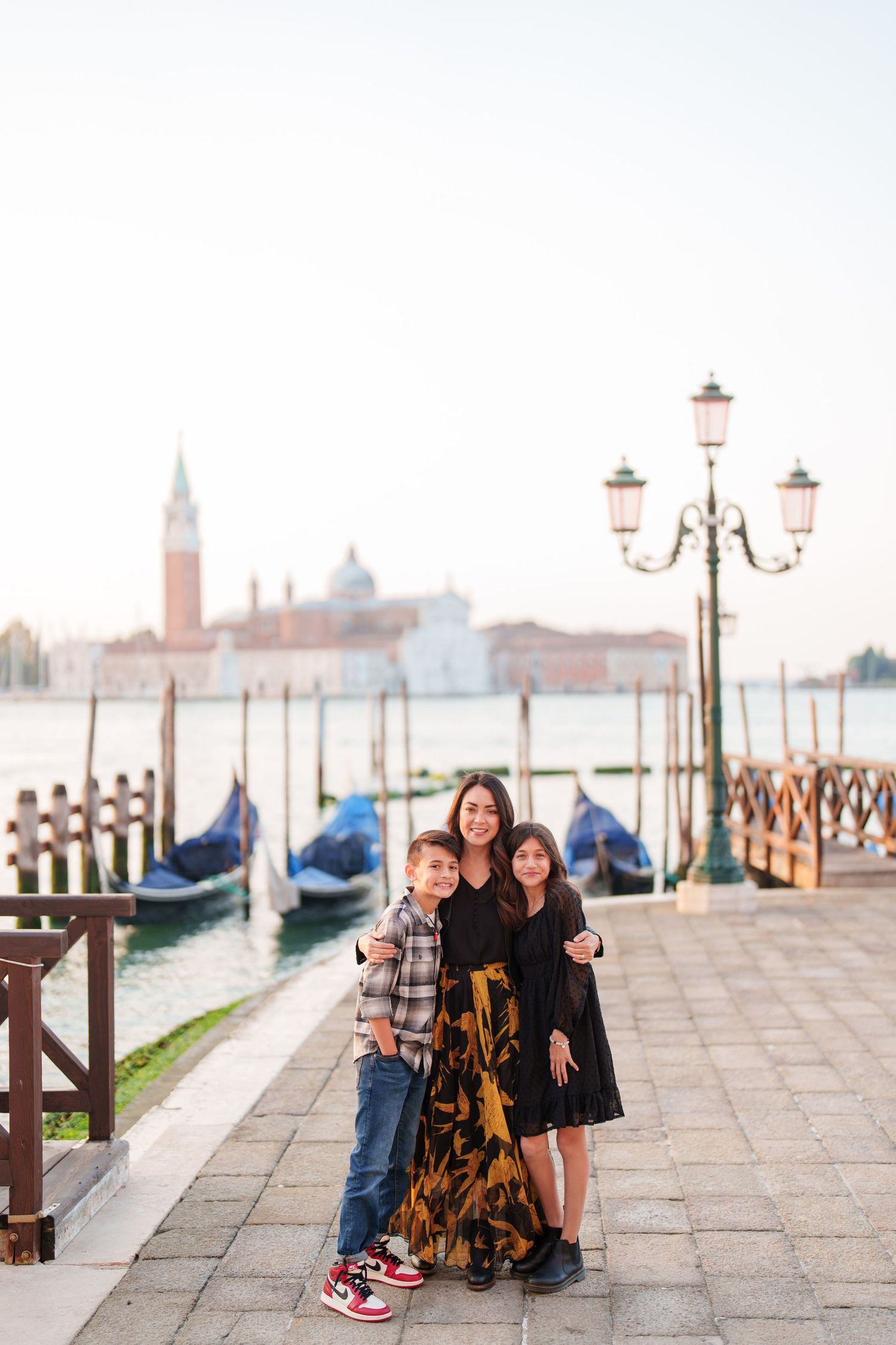 A group enjoying a scenic moment along the waterfront promenade in Venice with historic buildings in the background.