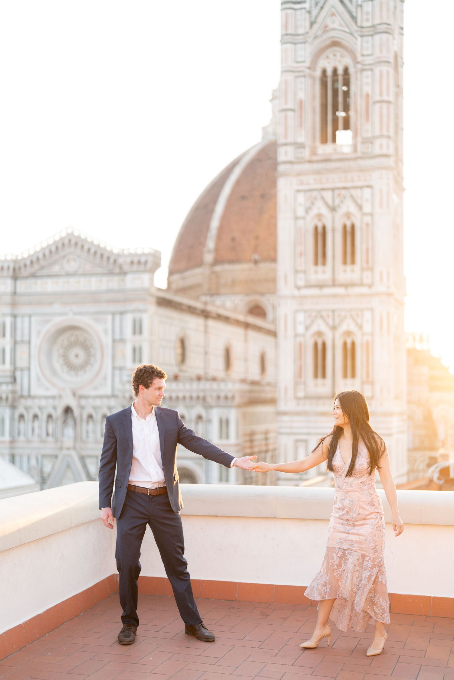 Romantic couple shares tender moments on a rooftop terrace overlooking the Florence Cathedral at sunset.