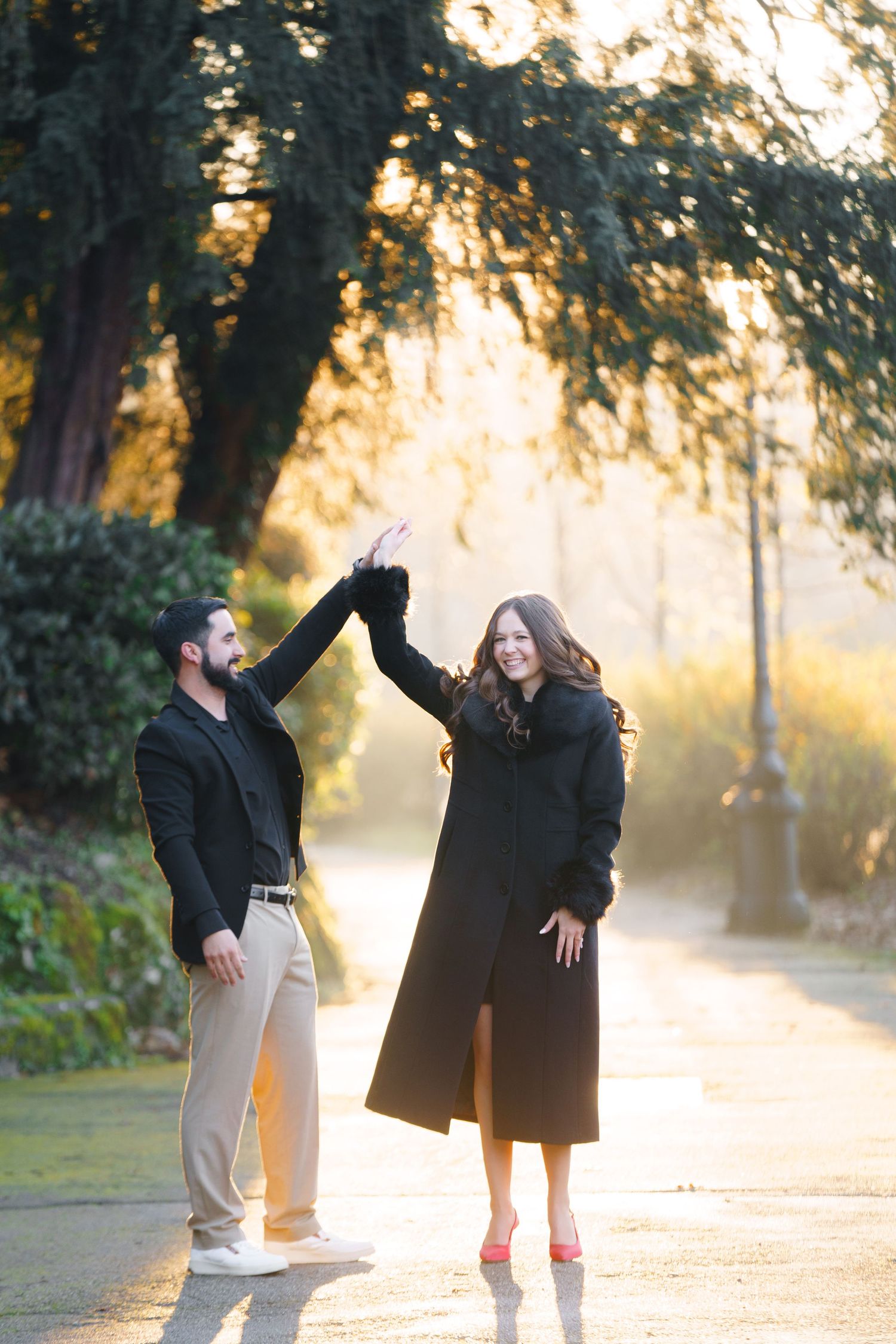 A couple shares playful moments during a golden hour photoshoot in a sunlit park setting.
