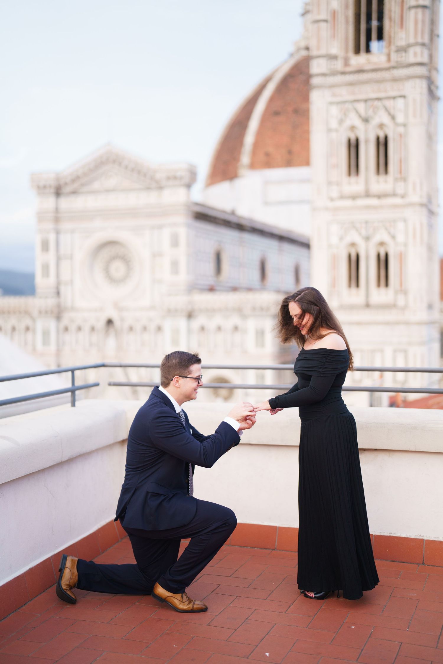 A romantic proposal moment on a rooftop terrace overlooking the iconic Duomo cathedral in Florence, Italy.