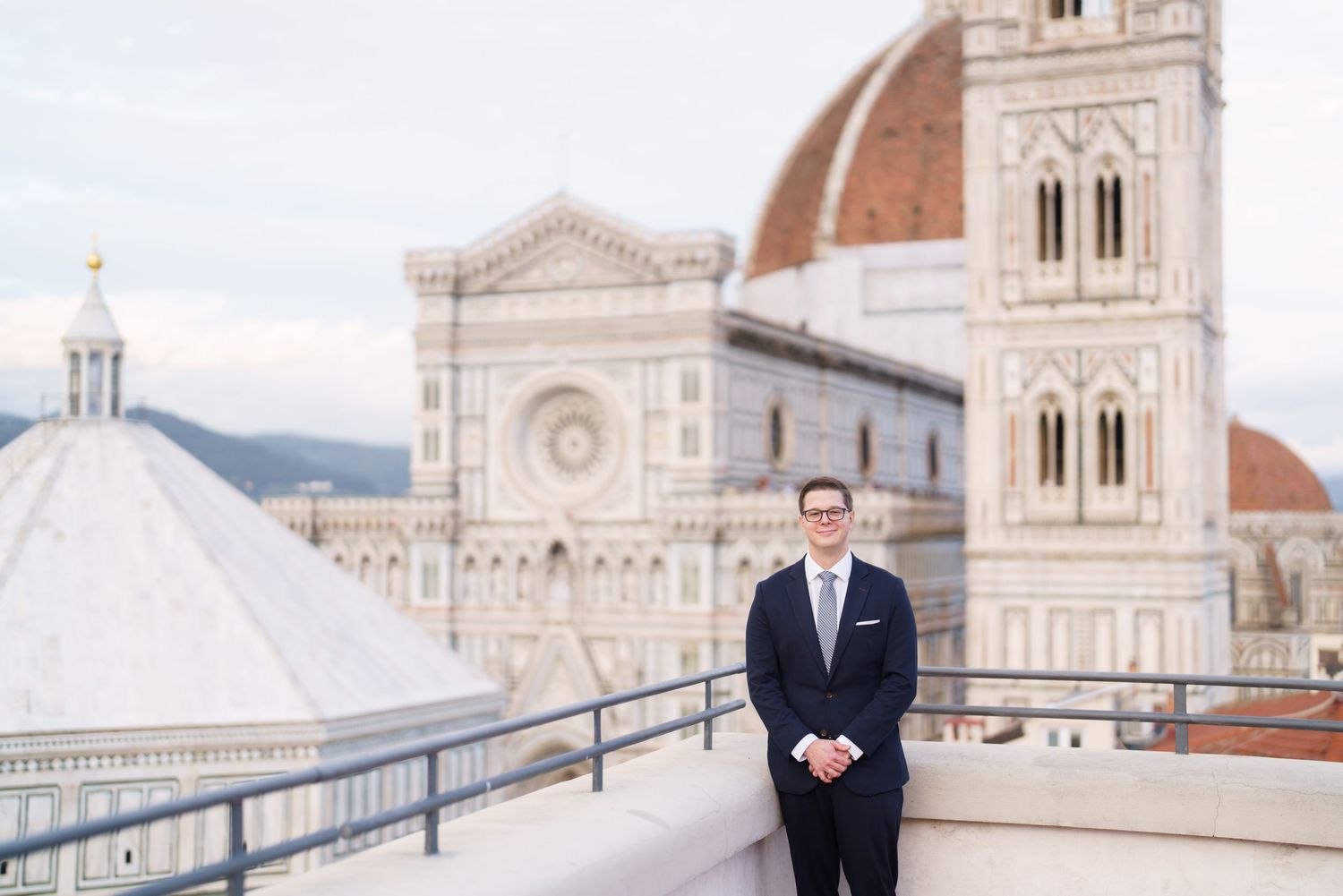 Elegant couple poses at Piazzale Michelangelo overlooking the historic Florence Cathedral and cityscape at sunset.