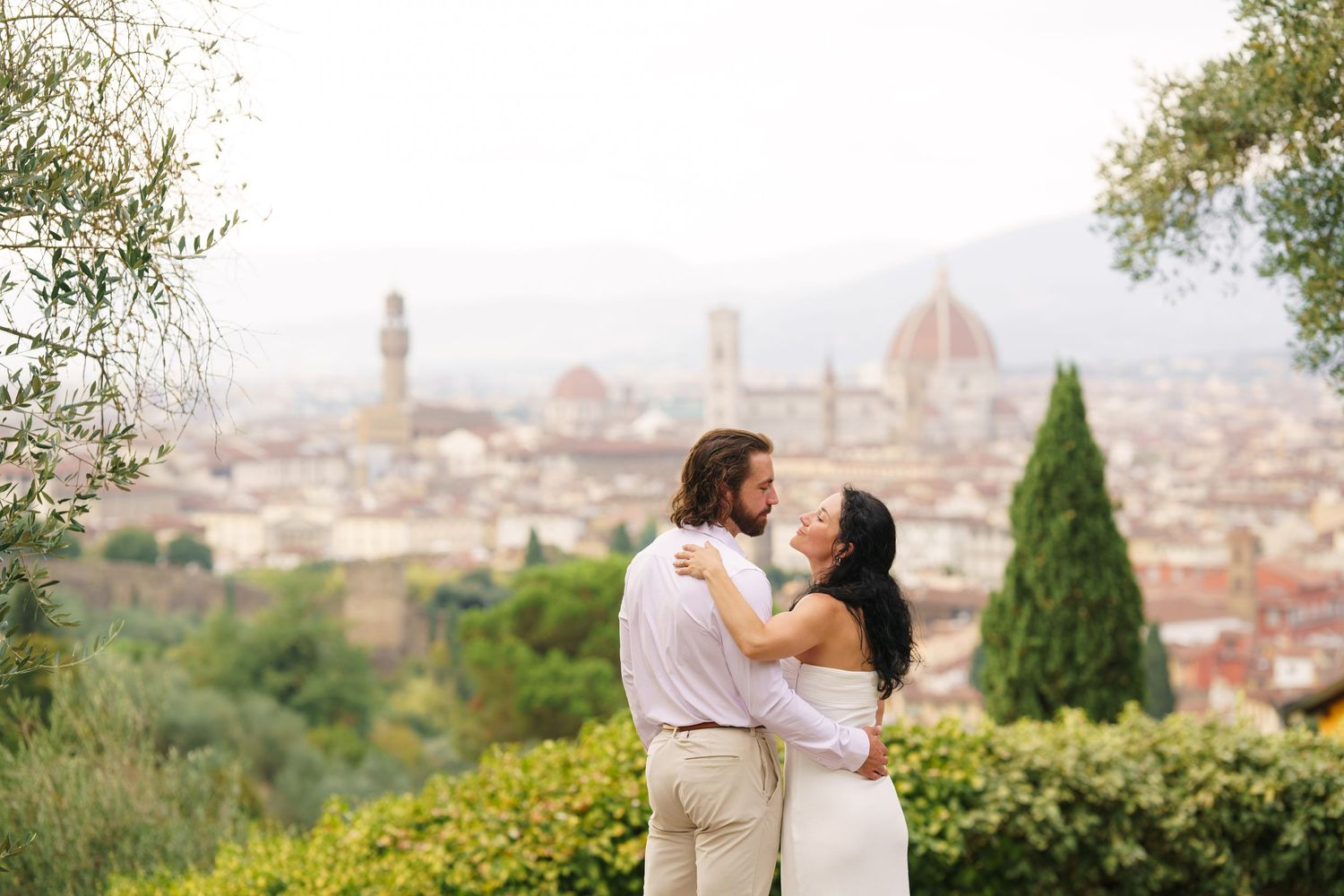 A romantic couple embraces while overlooking the stunning cityscape of Florence, Italy with its iconic Duomo cathedral.