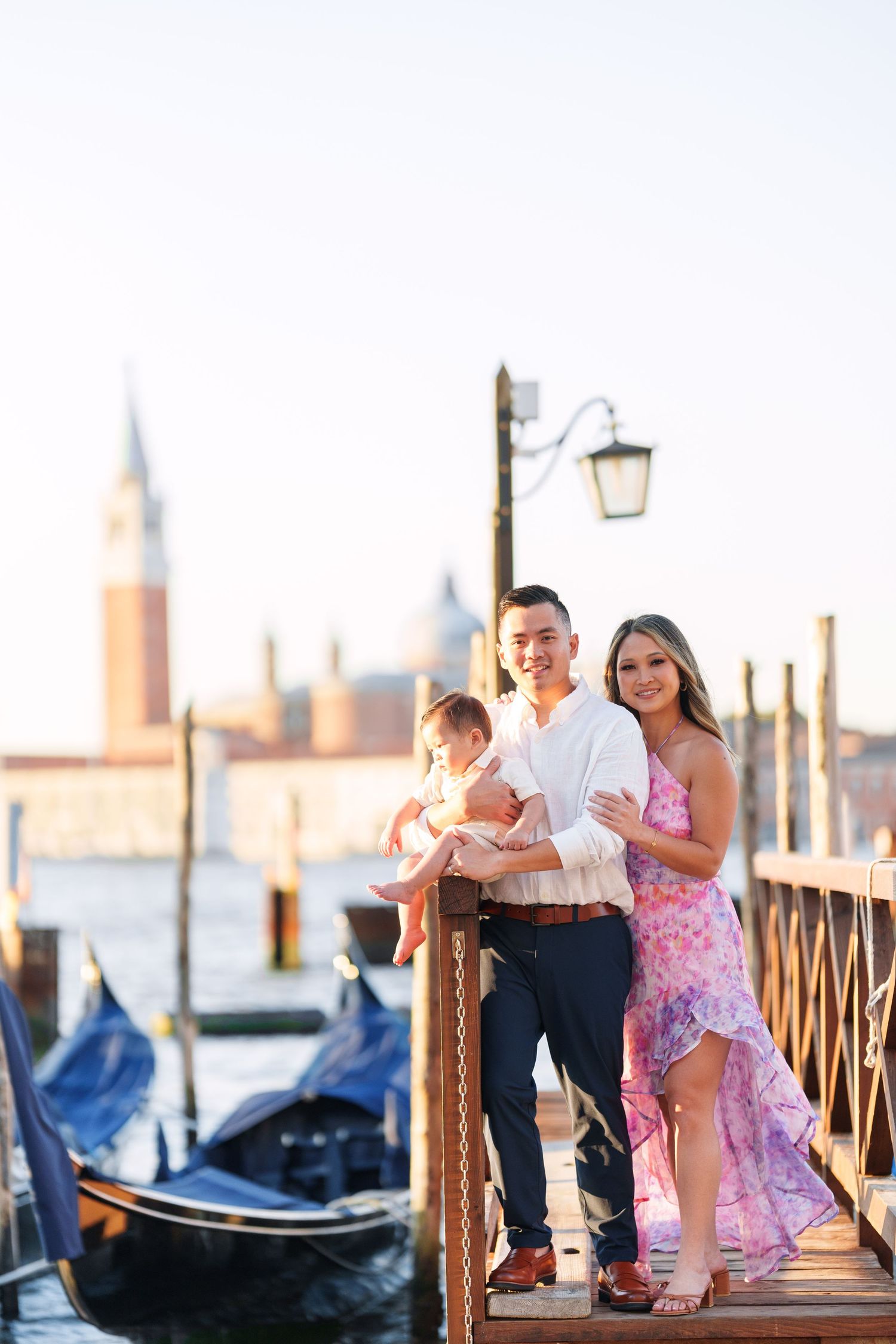 Family posing on Venice dock with gondolas and San Giorgio Maggiore in background at golden hour.