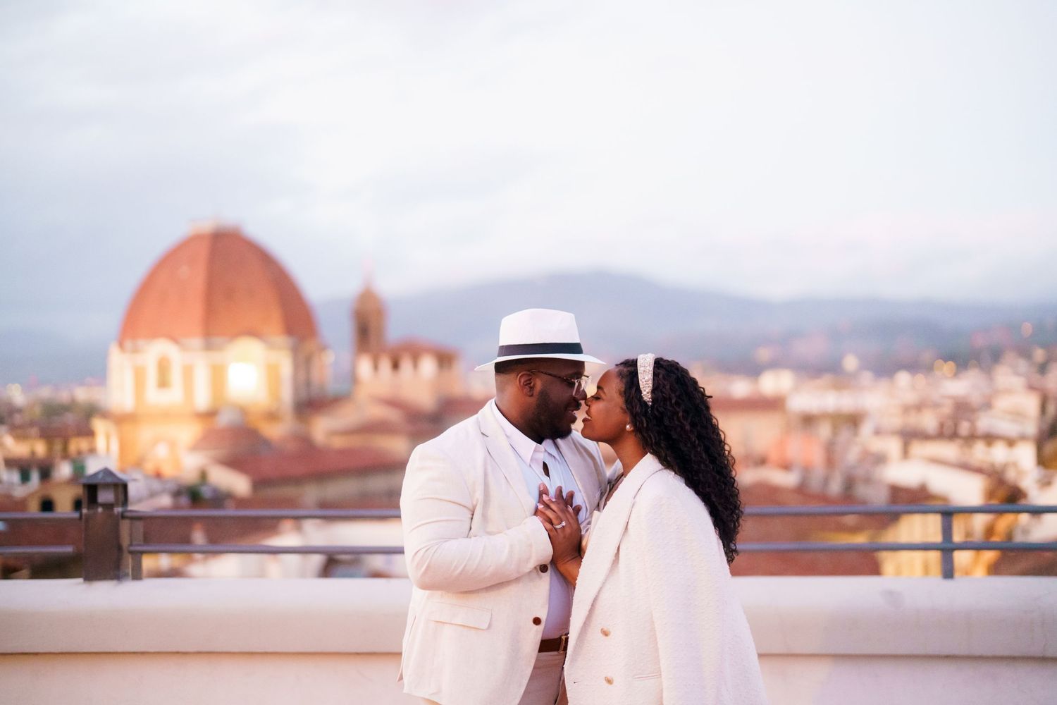 Couple sharing a romantic moment on a rooftop in Florence, Italy, with the Duomo cathedral in the background.